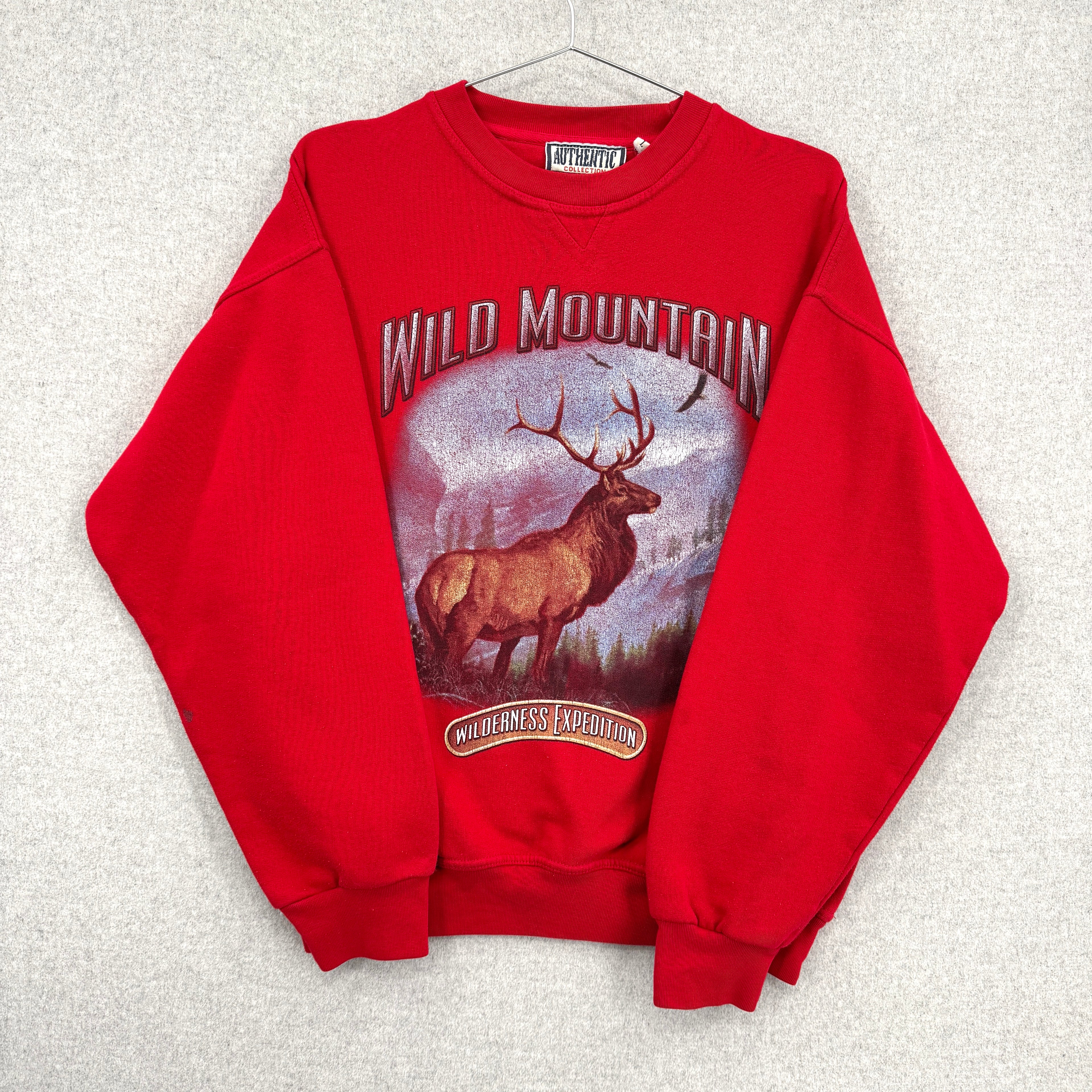 Red sweatshirt with a elk graphic and 'Wild Mountain' text on a textured white background