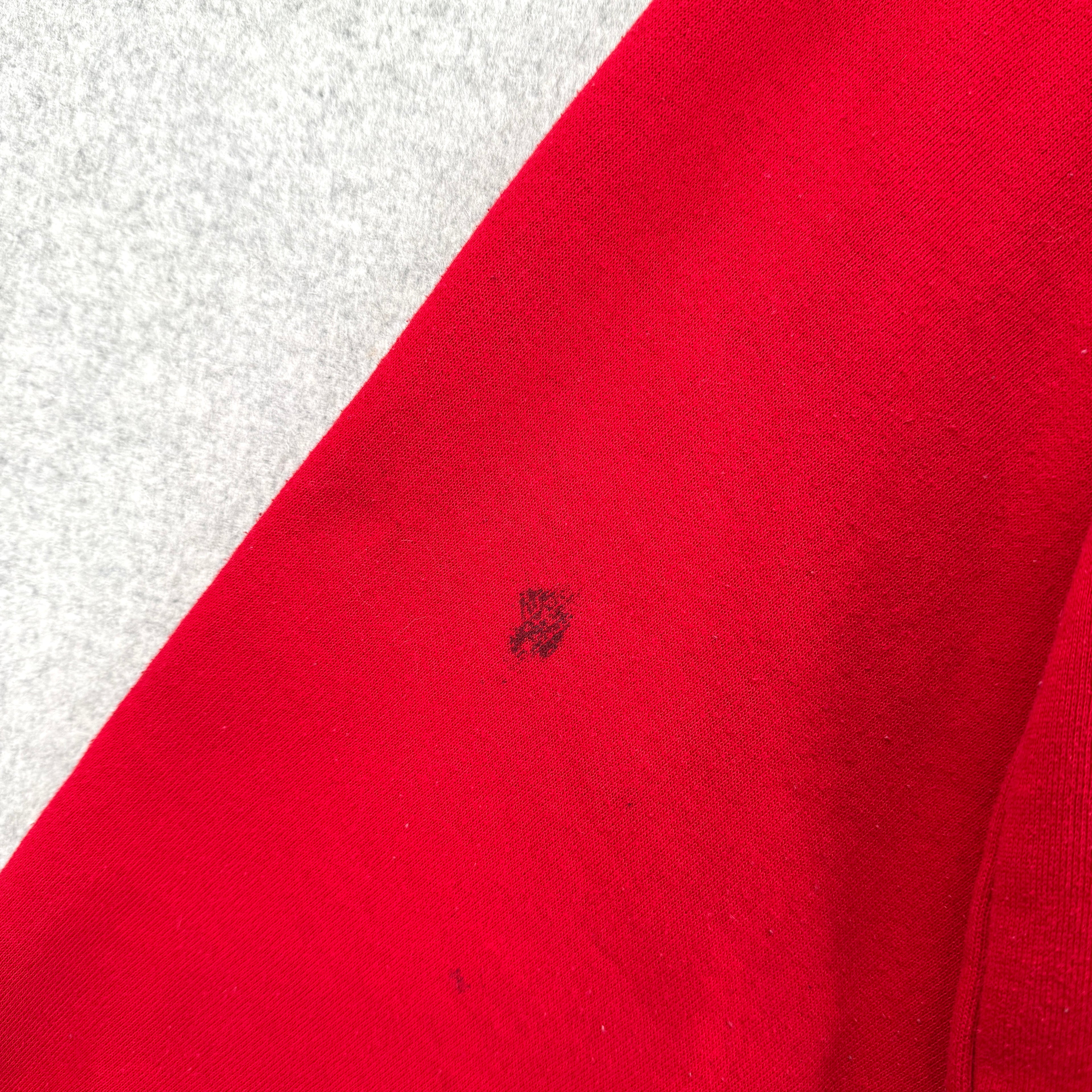Close-up of a red fabric with a small black spot on a white background