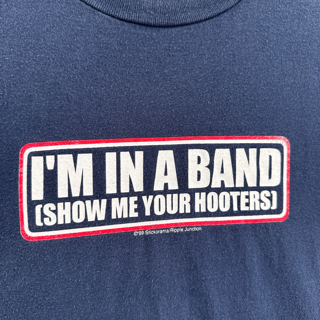Navy blue shirt with a humorous text patch on a plain background. "I'm in a band show me your hooters"