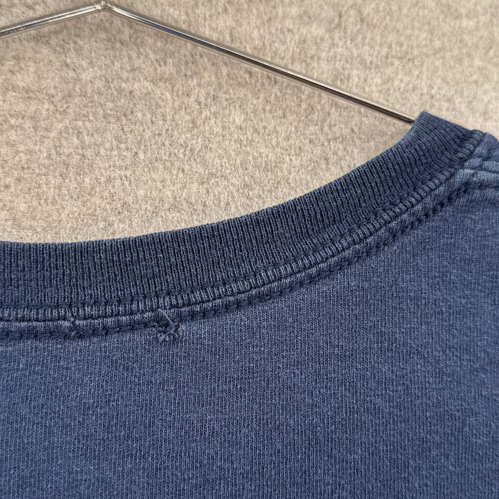 Close-up of a blue sweatshirt collar on a hanger with a neutral background. Small hole on back of collar
