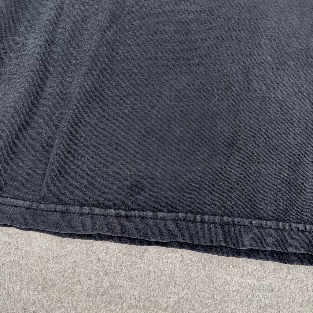 Close-up of a dark gray fabric with a visible stain spot on a light gray background