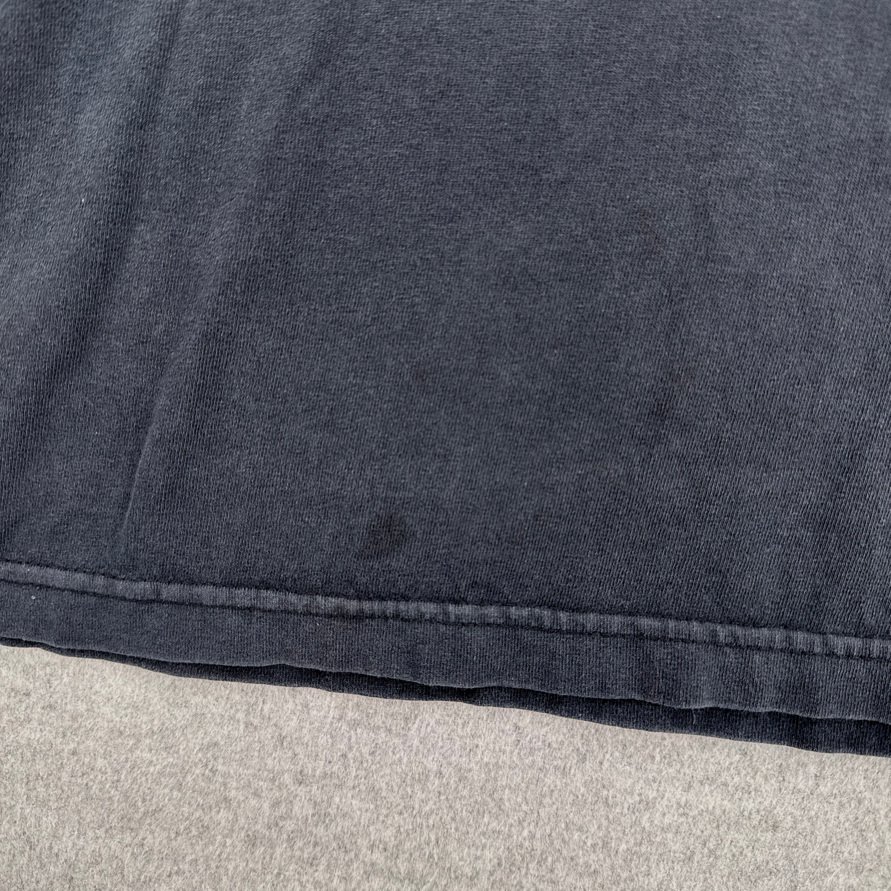 Close-up of a dark gray fabric with a visible stain spot on a light gray background
