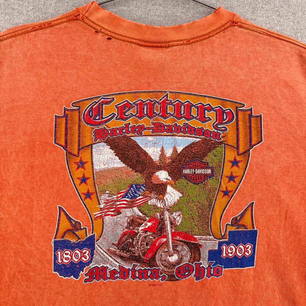 Orange t-shirt with graphic design featuring an eagle, American flag, and text on a gray surface.