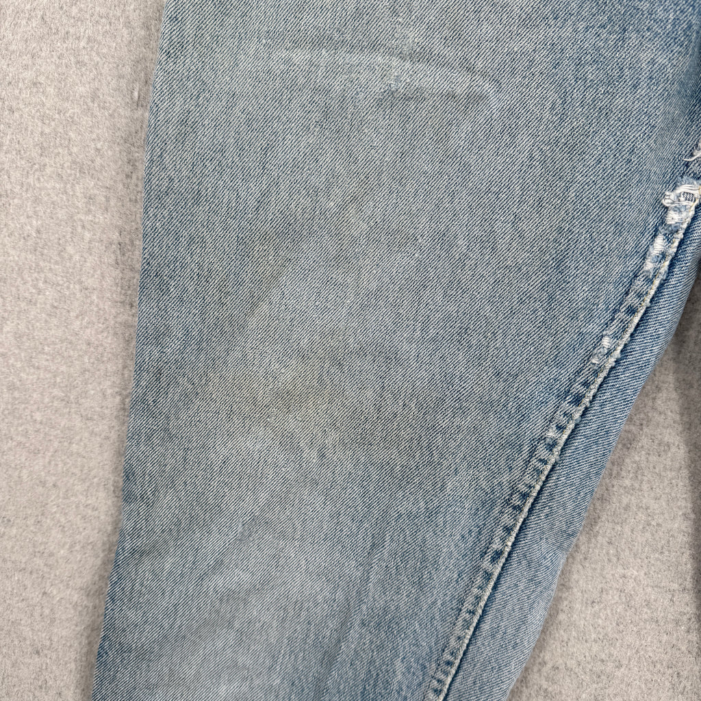 Close-up of blue jeans on a beige carpet showing discolouration and fraying