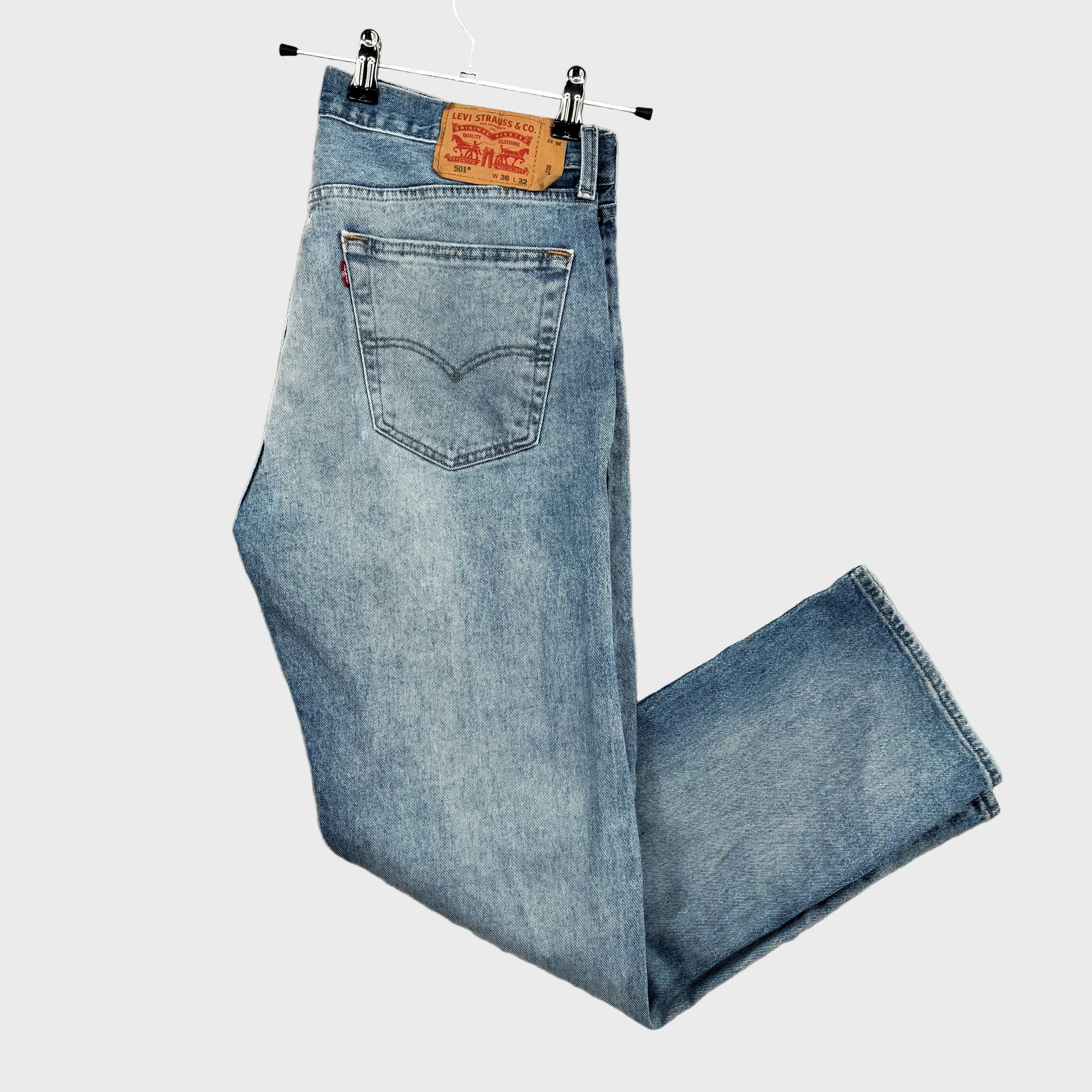 Pair of blue jeans on a hanger with Levi's label against a beige background