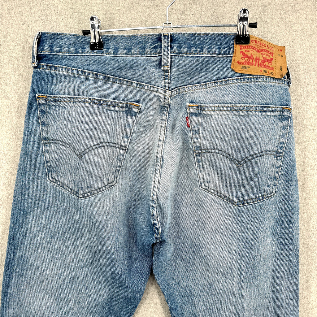 Blue jeans with a Levi's tag on a beige background. back showing pockets