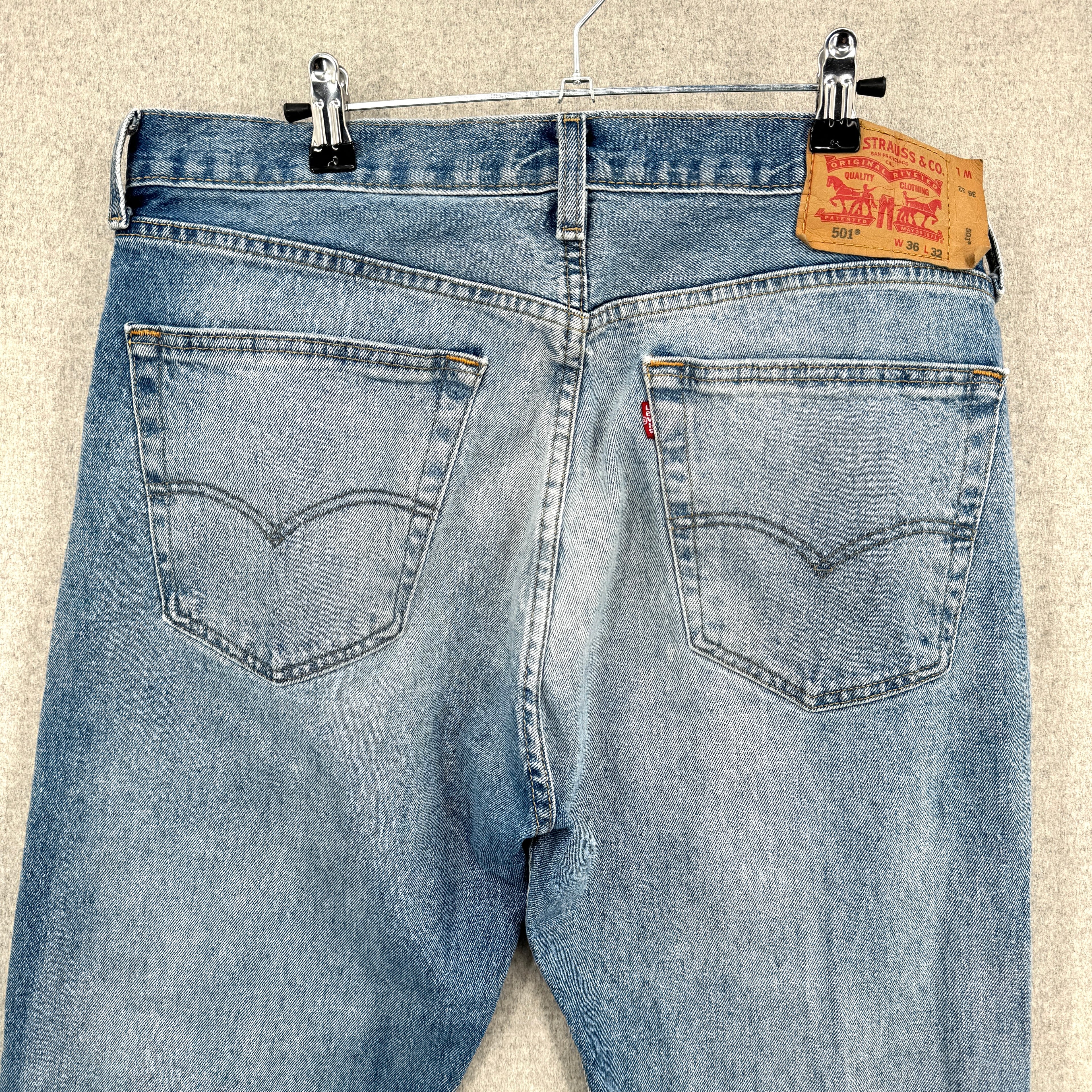 Blue jeans with a Levi's tag on a beige background. back showing pockets
