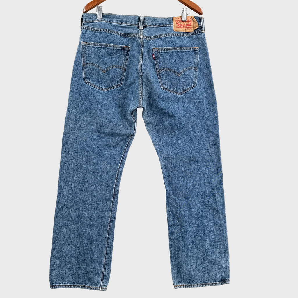 Pair of blue jeans laid flat on a gray surface