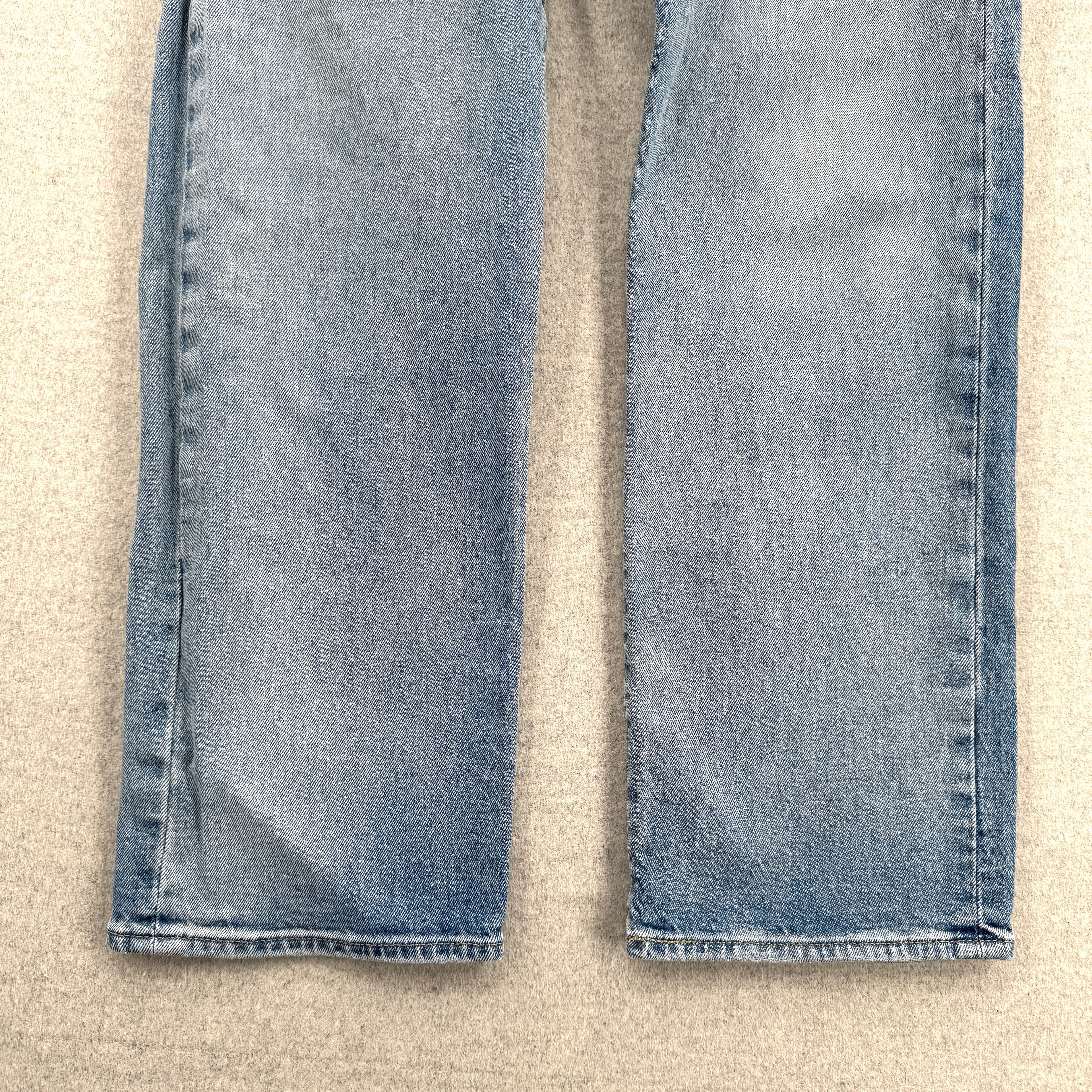 Folded blue jeans on a beige surface. Bottom of pants front