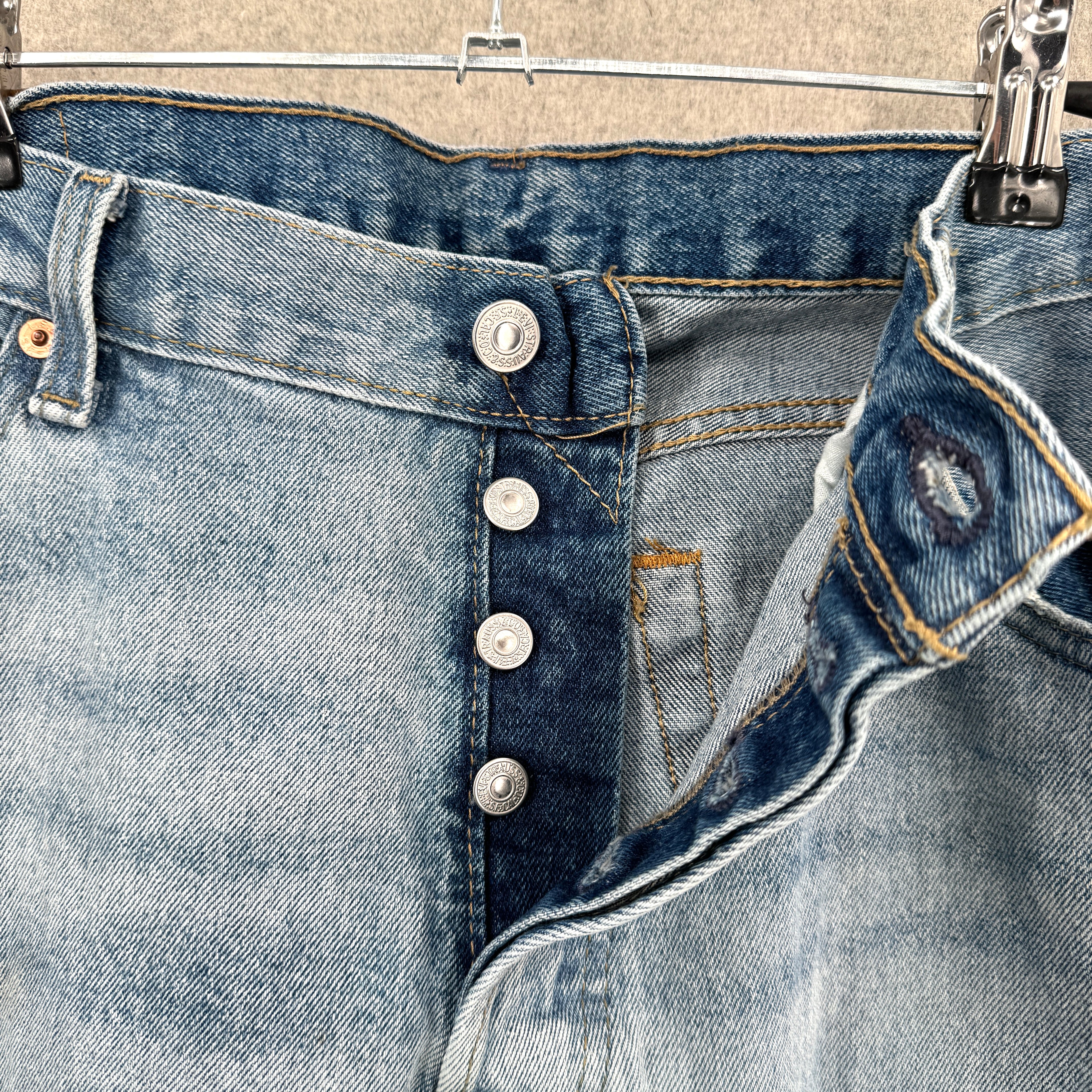 Close-up of a blue denim jeans with buttons and stitching details.