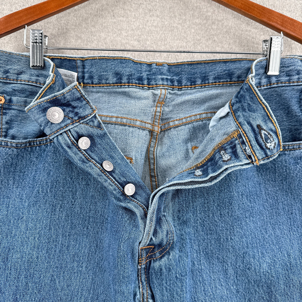 Close-up of a blue denim pants with buttons on a neutral background