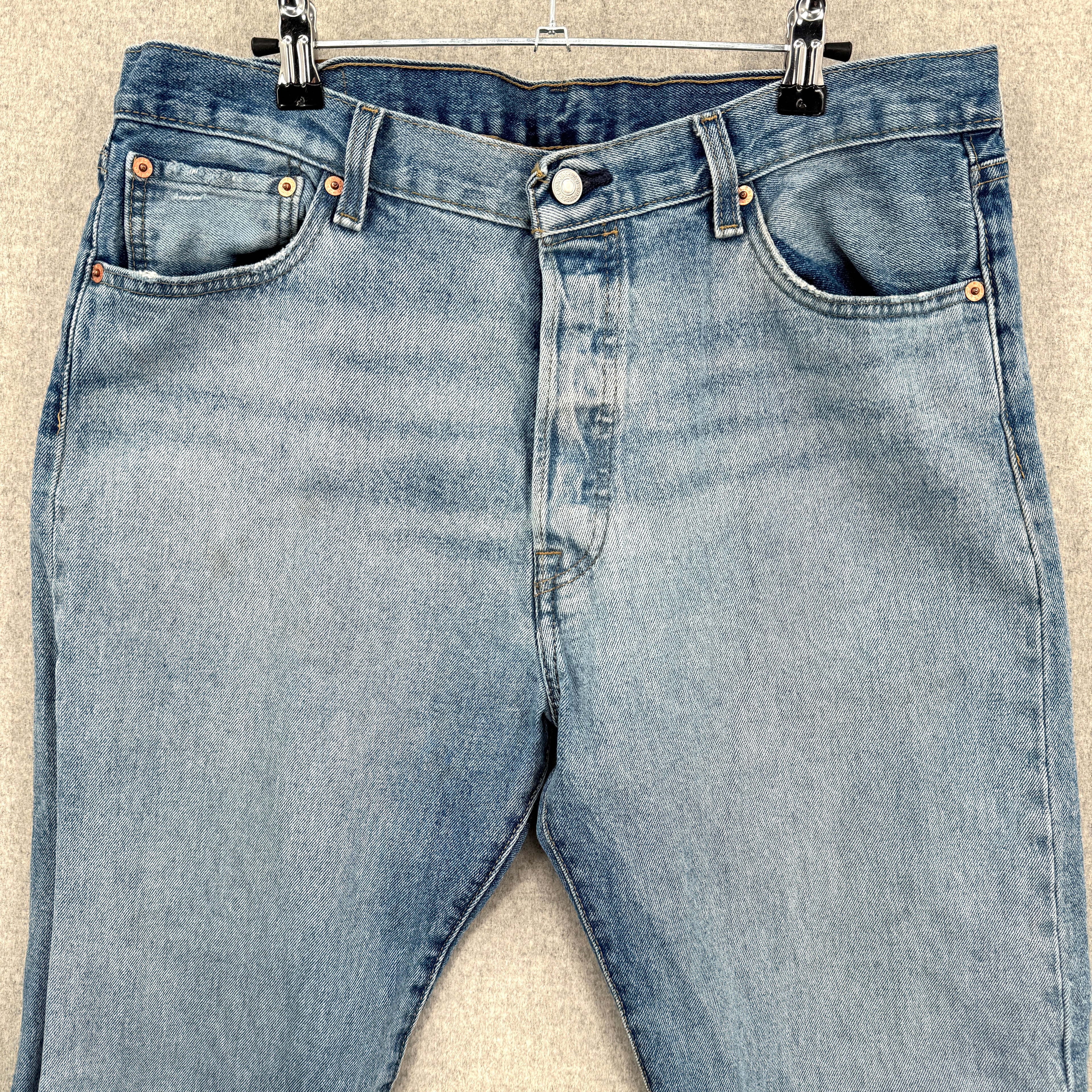 Pair of blue jeans on a hanger against a neutral background