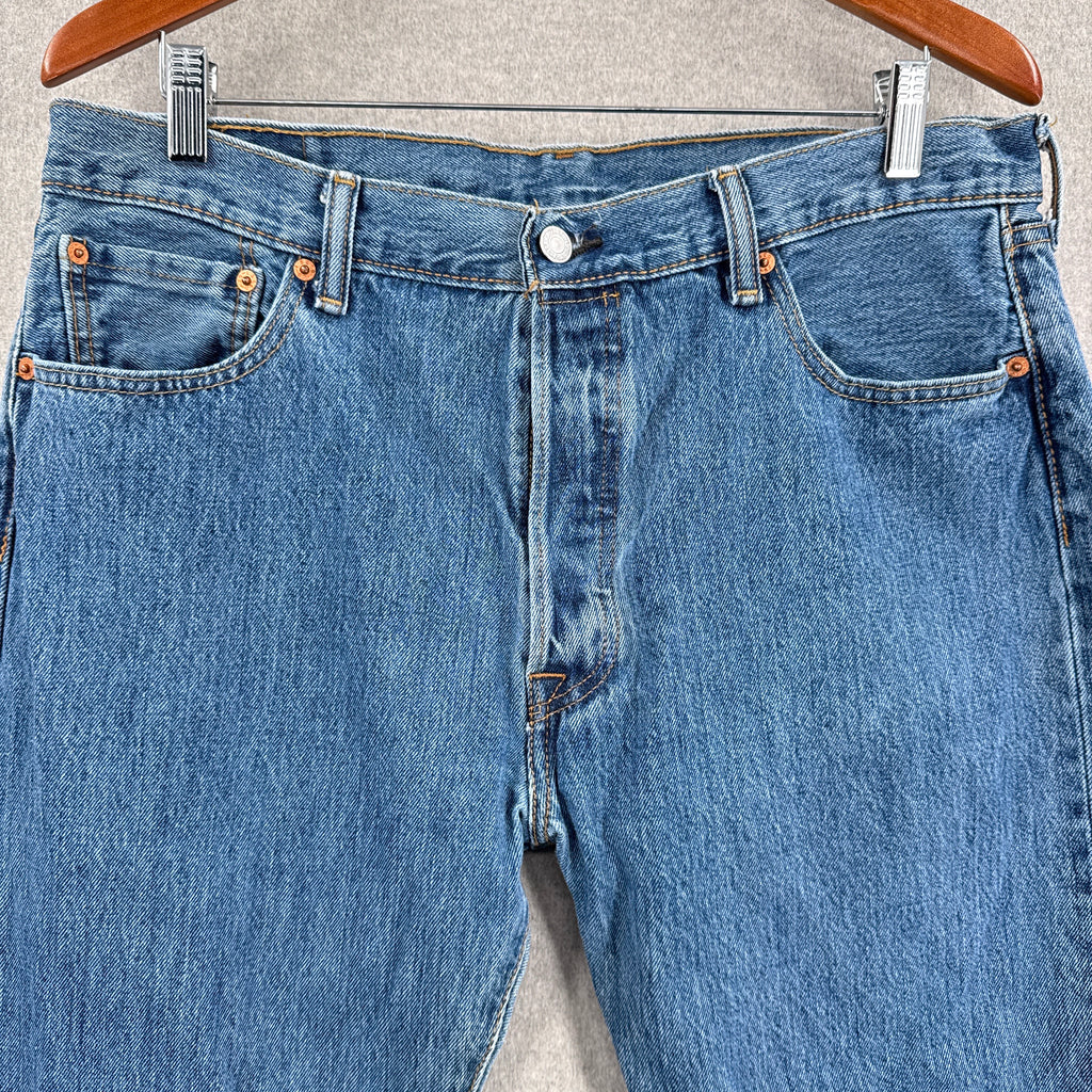 Blue jeans hanging on a hanger with a neutral background