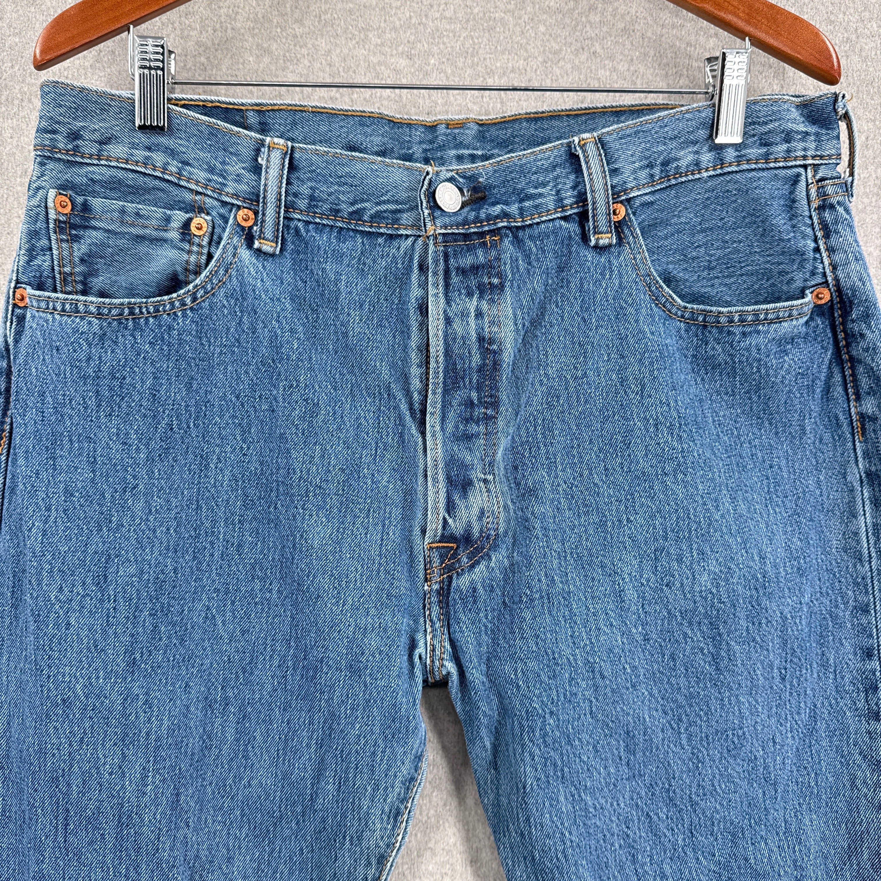 Blue jeans hanging on a hanger with a neutral background