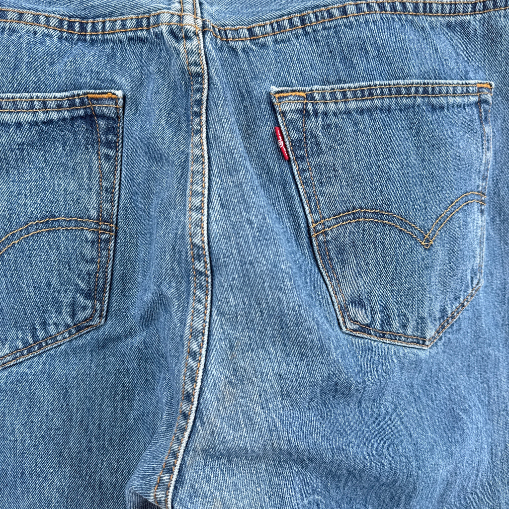 Close-up of blue denim jeans with a brand logo on the pocket.