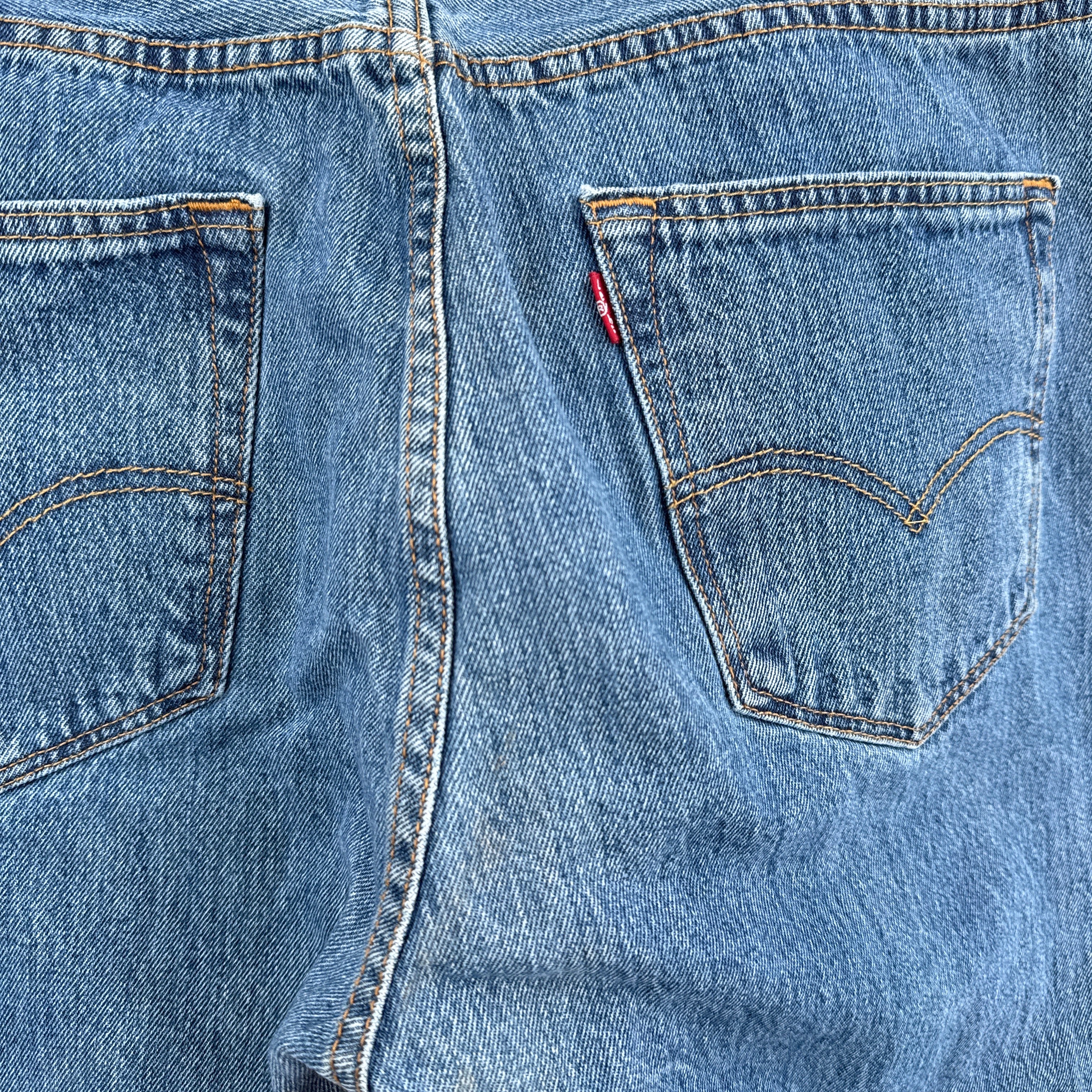 Close-up of blue denim jeans with a brand logo on the pocket.