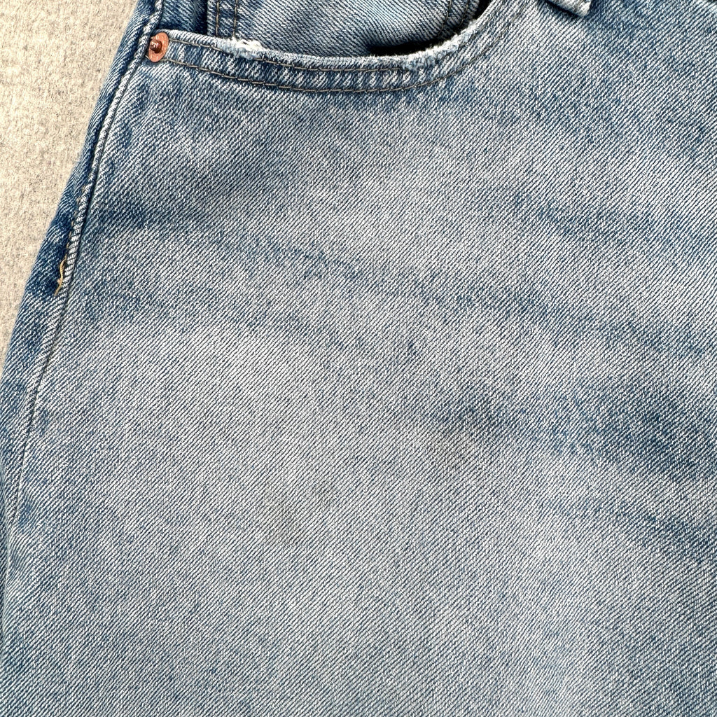 Close-up of blue denim fabric with stitching details. small stain spots around pocket
