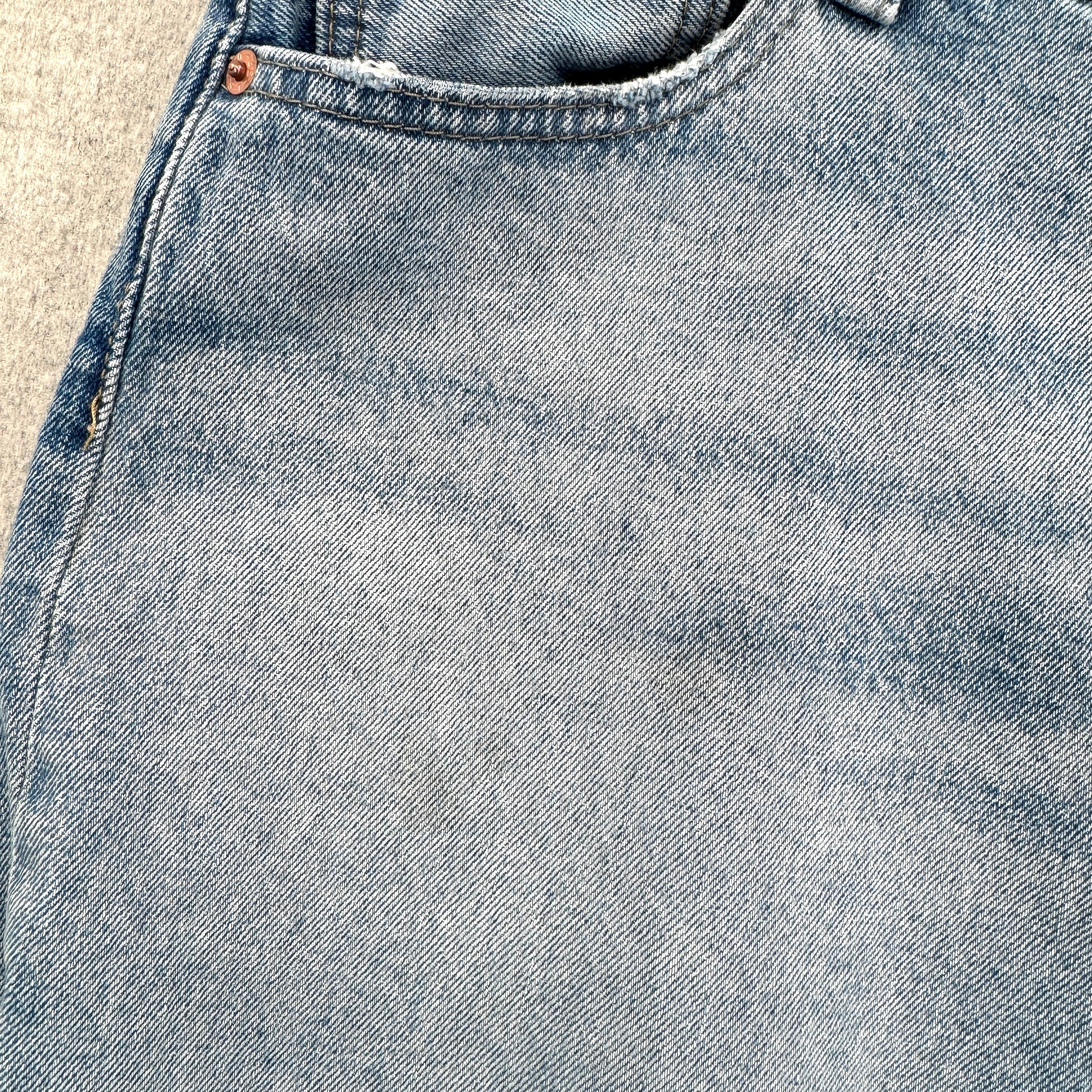 Close-up of blue denim fabric with stitching details. small stain spots around pocket