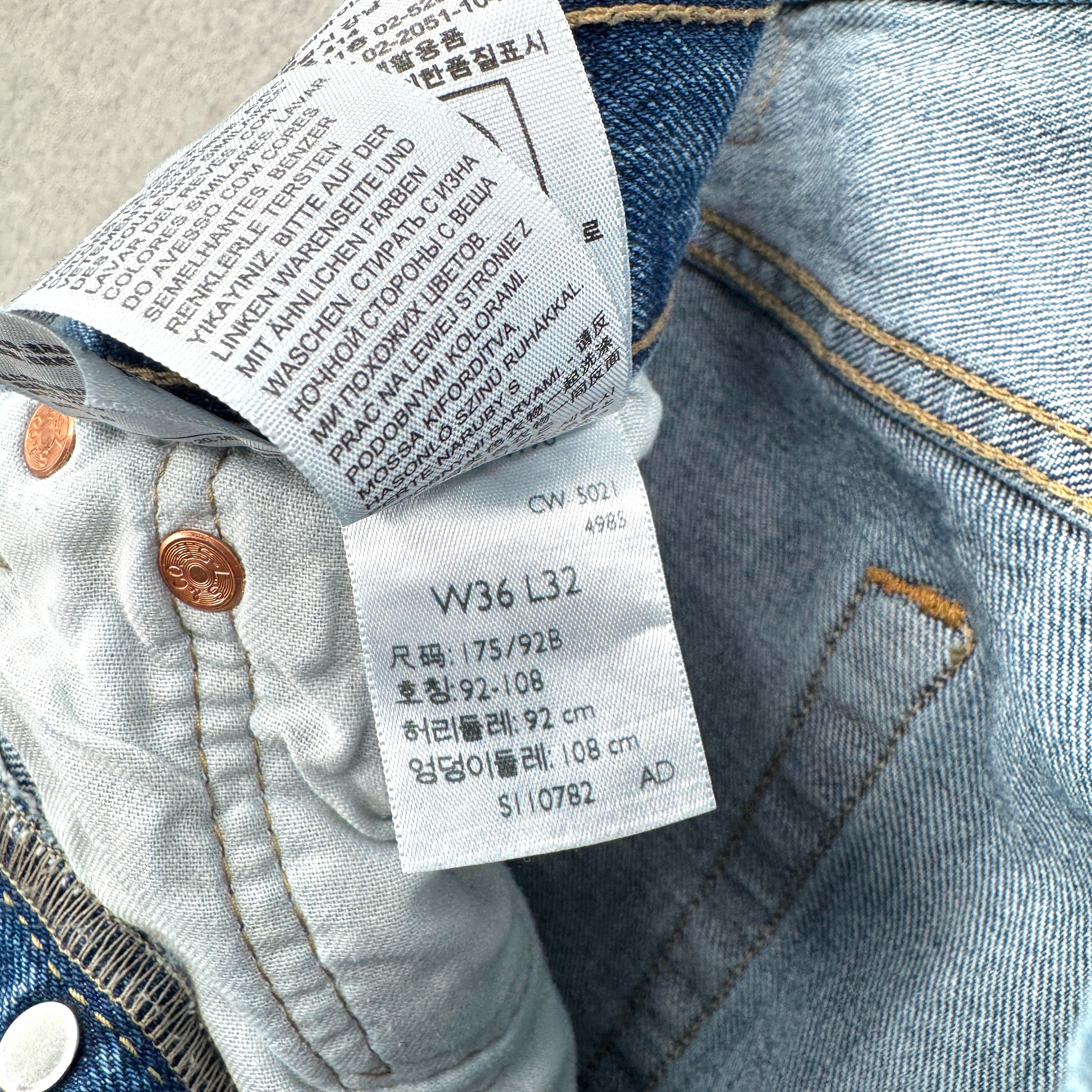 Close-up of denim jeans with a label showing size and care instructions.