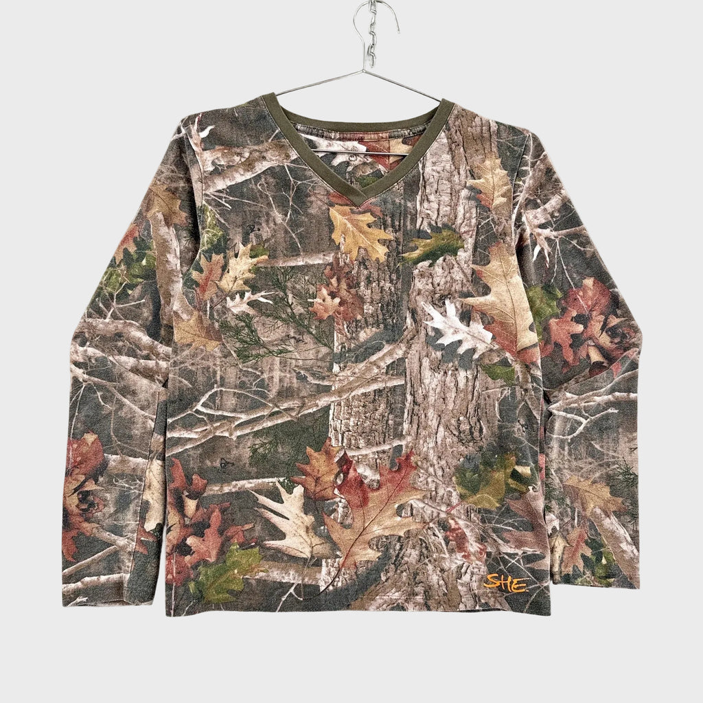 Camouflage-patterned long-sleeve shirt on a hanger against a light gray background