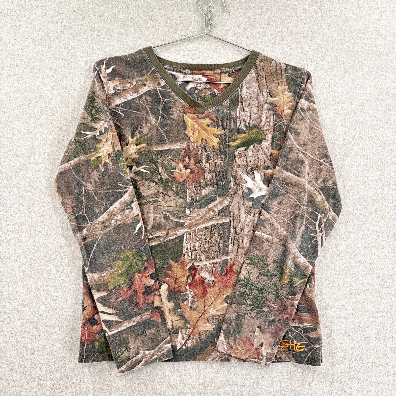 Camouflage-patterned long-sleeve shirt on a hanger against a light background