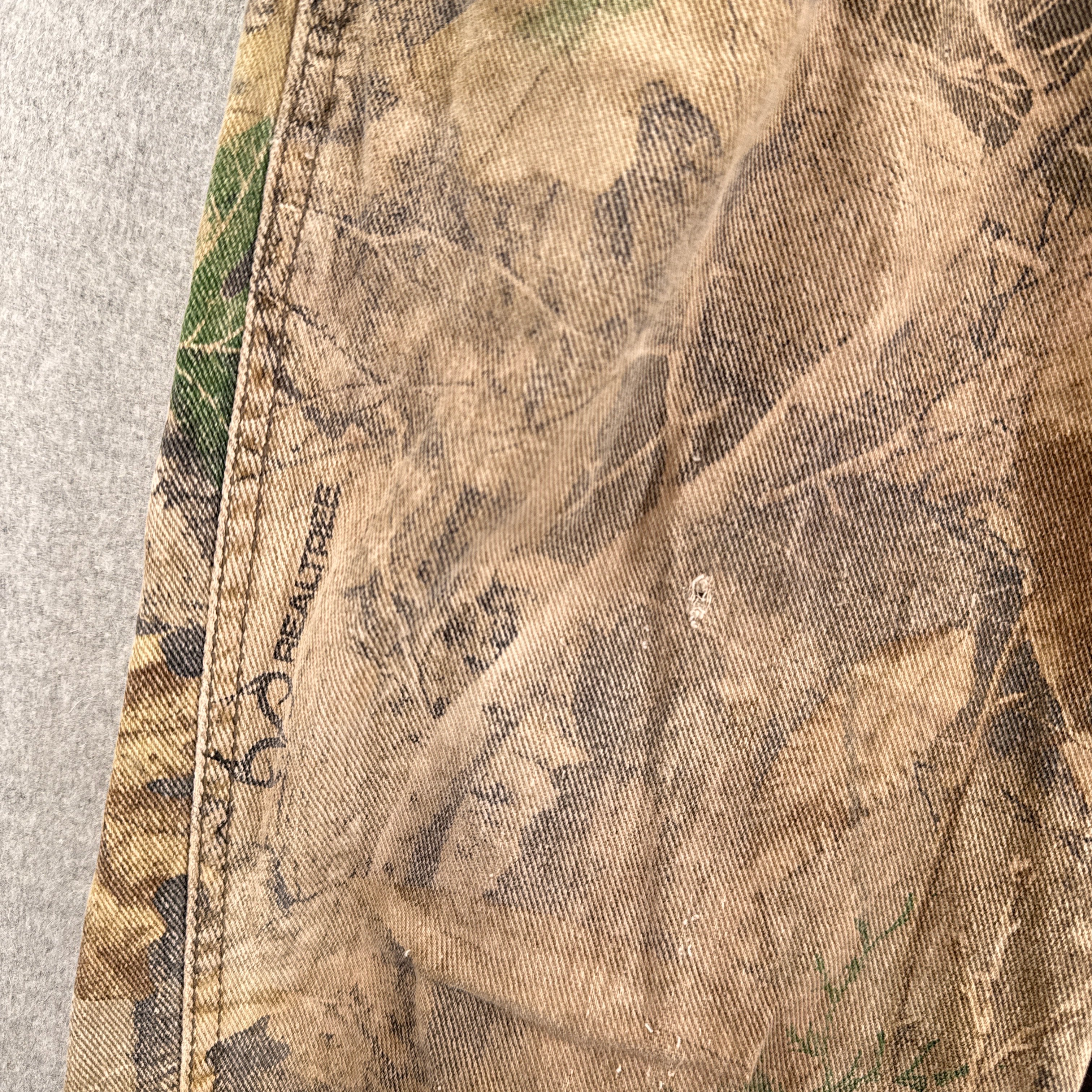 Close-up of a camouflage-patterned fabric with 'RealTree' branding. small hole
