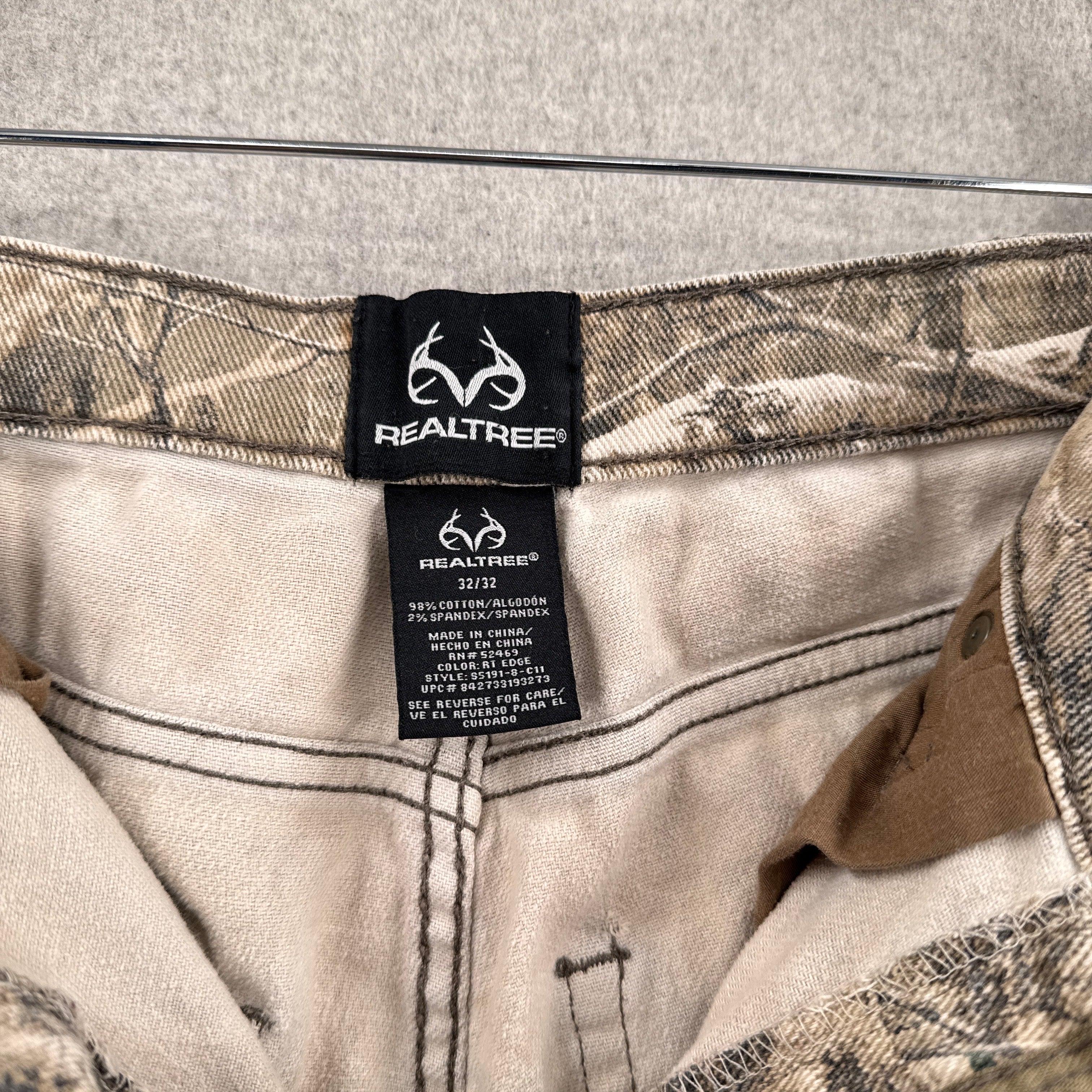 Realtree brand label on a camouflage pants. Tag reads size 32, 98% cotton 2% spandex
