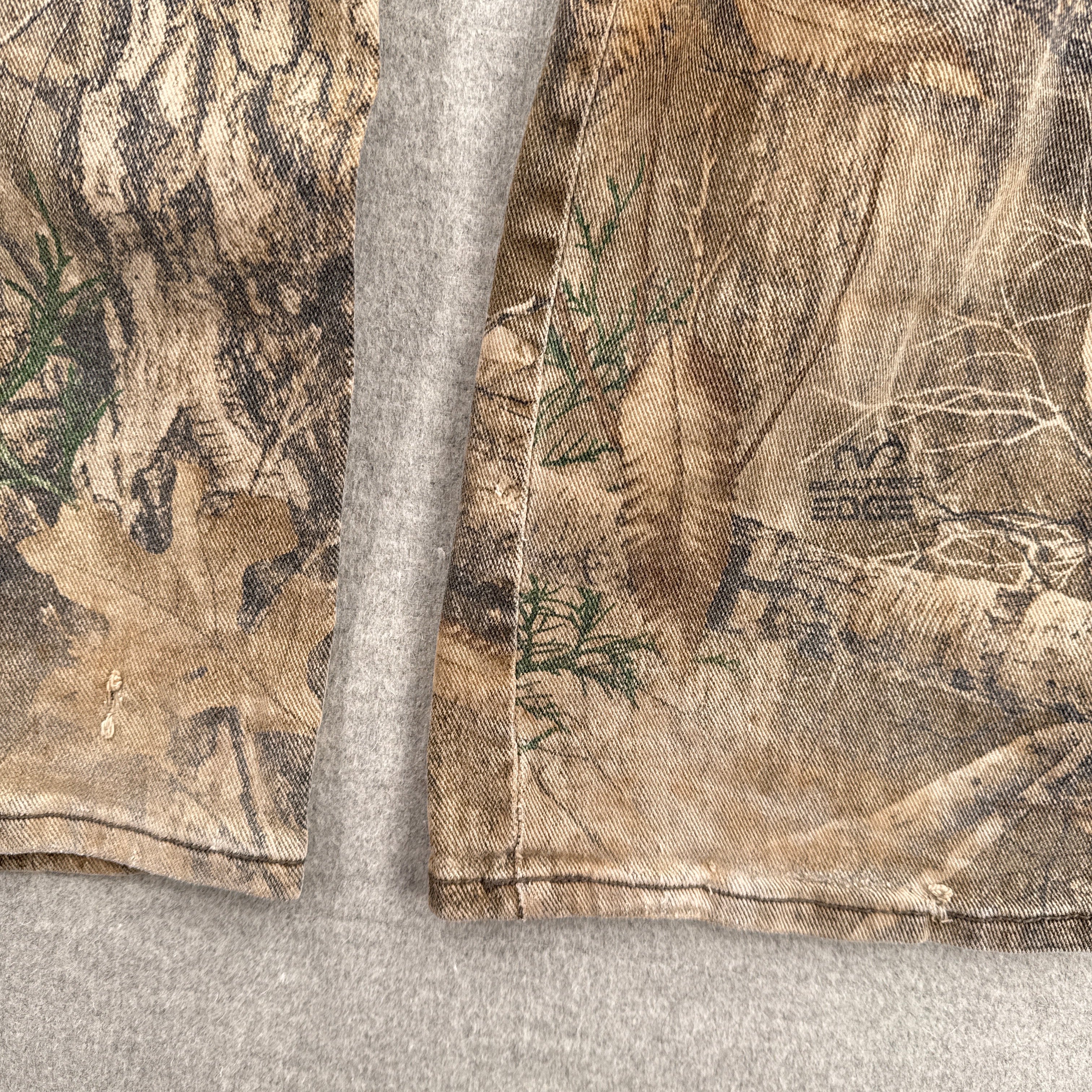 Close-up of camouflage-patterned fabric on a gray background. bottom back of pants have some small holes