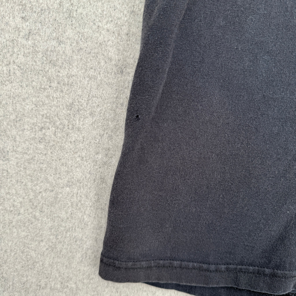 Close-up of dark gray fabric on a textured surface. small hole near bottom
