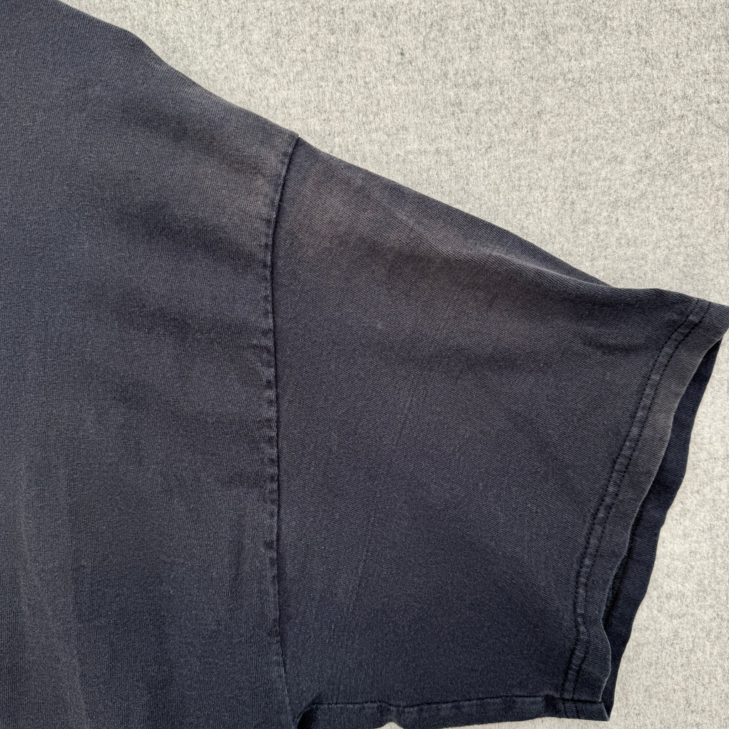 Close-up of a sleeveless dark shirt on a textured surface, faded fabric