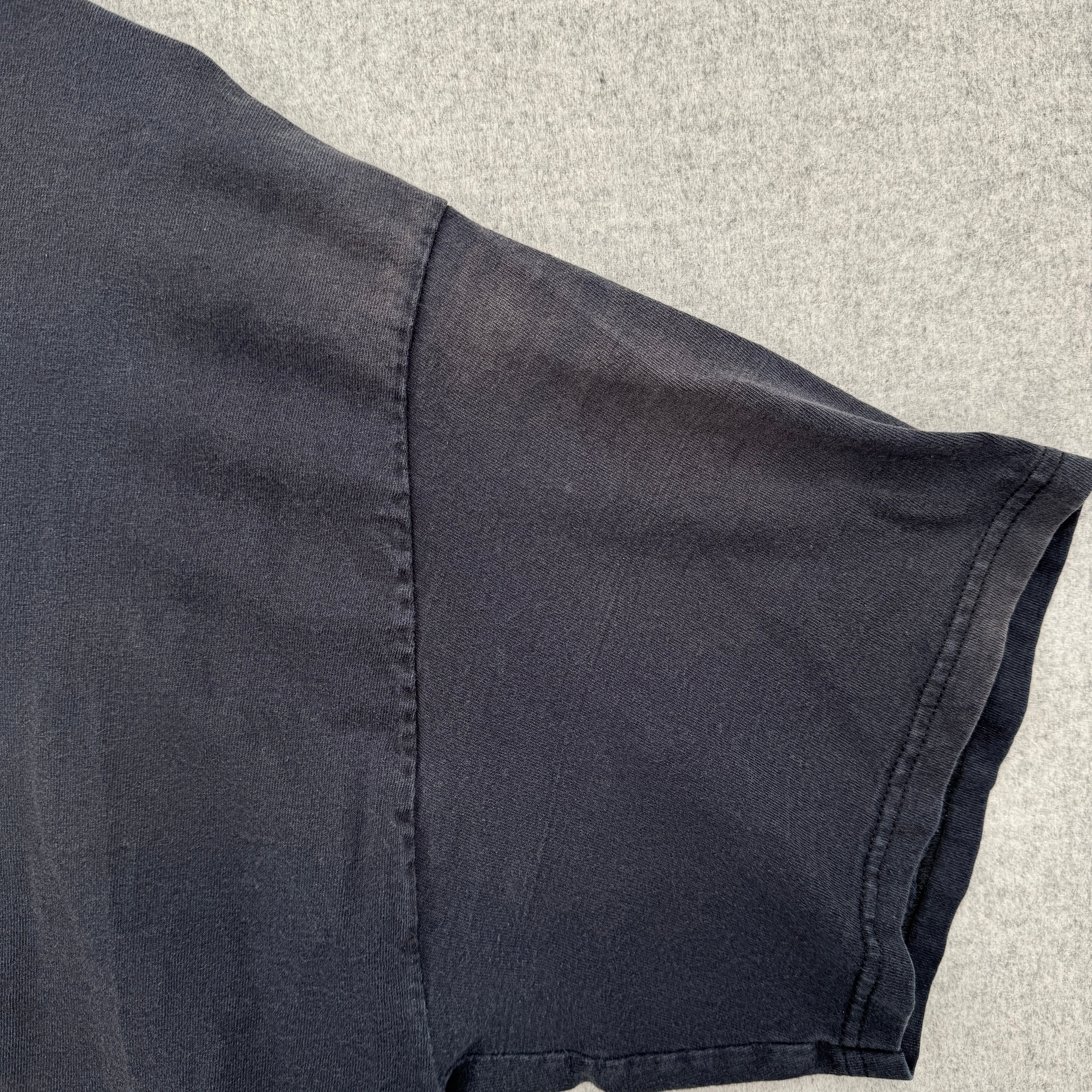 Close-up of a sleeveless dark shirt on a textured surface, faded fabric