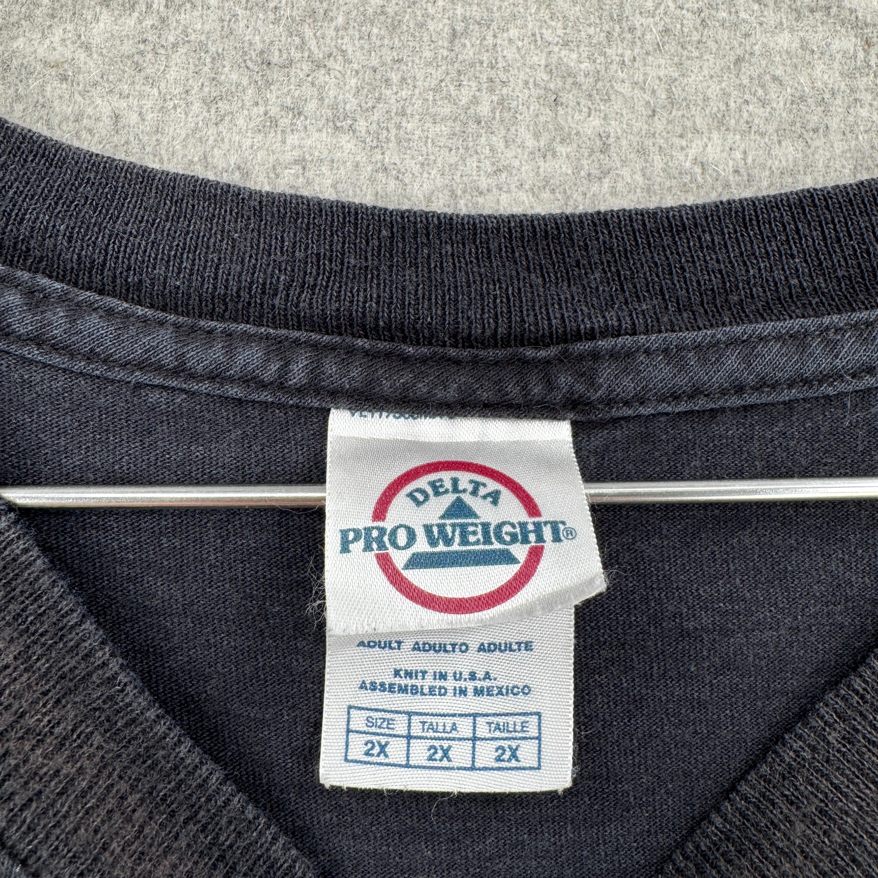Close-up of a Delta Pro Weight label on a dark fabric background. size 2XL
