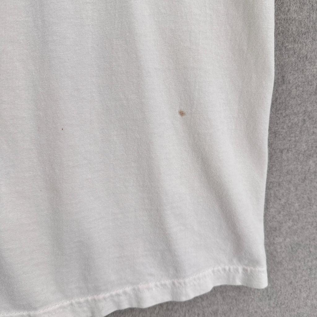 Close-up of a white fabric surface with a small brown spot on a gray background
