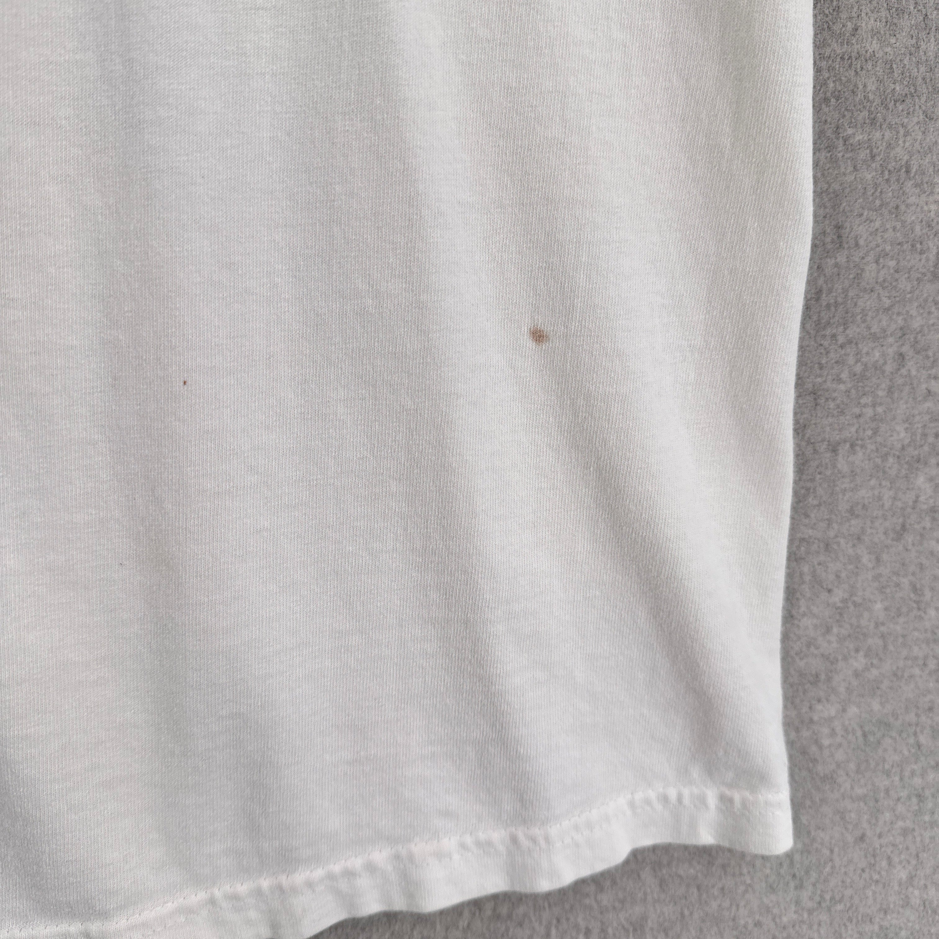 Close-up of a white fabric surface with a small brown spot on a gray background