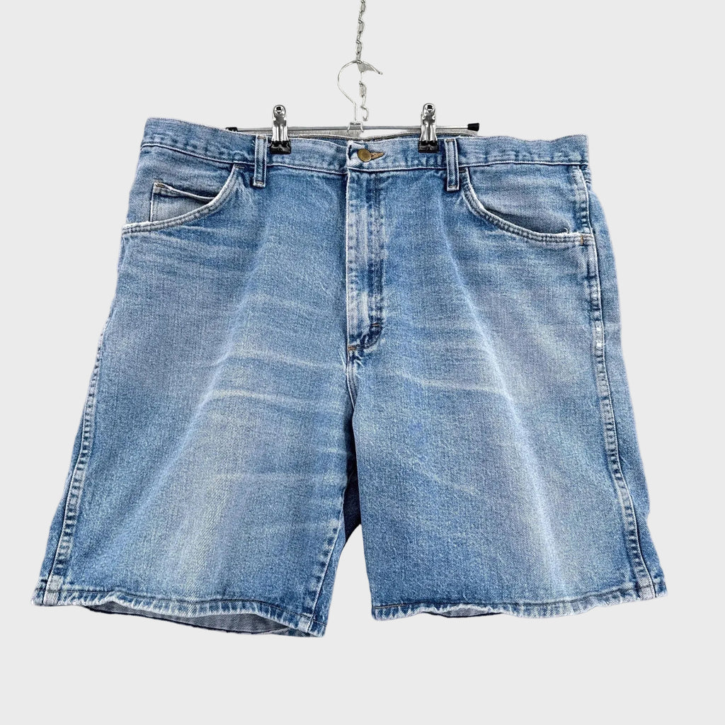 Blue denim shorts hanging on a gray background