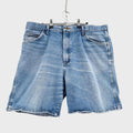 Blue denim shorts hanging on a gray background
