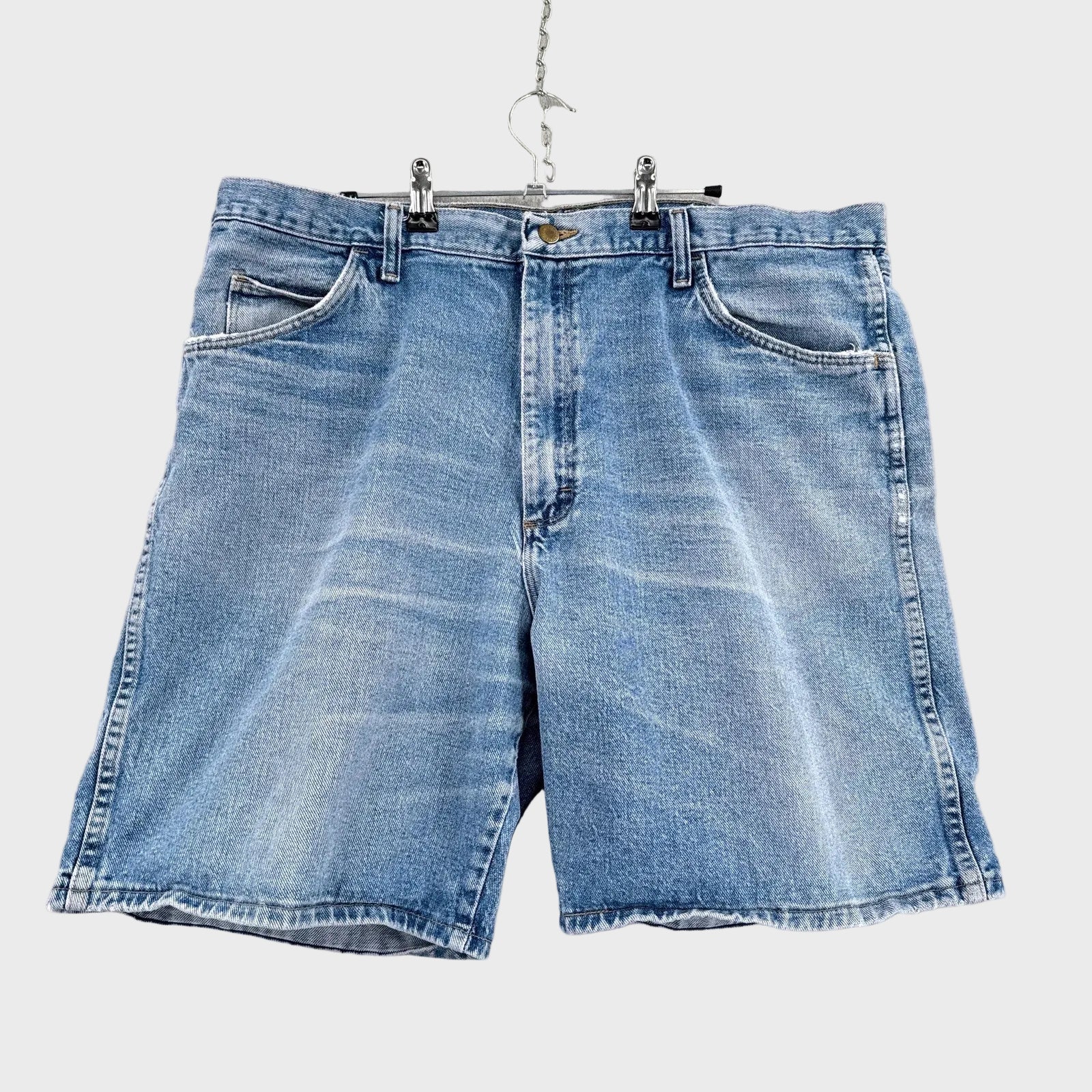 Blue denim shorts hanging on a gray background
