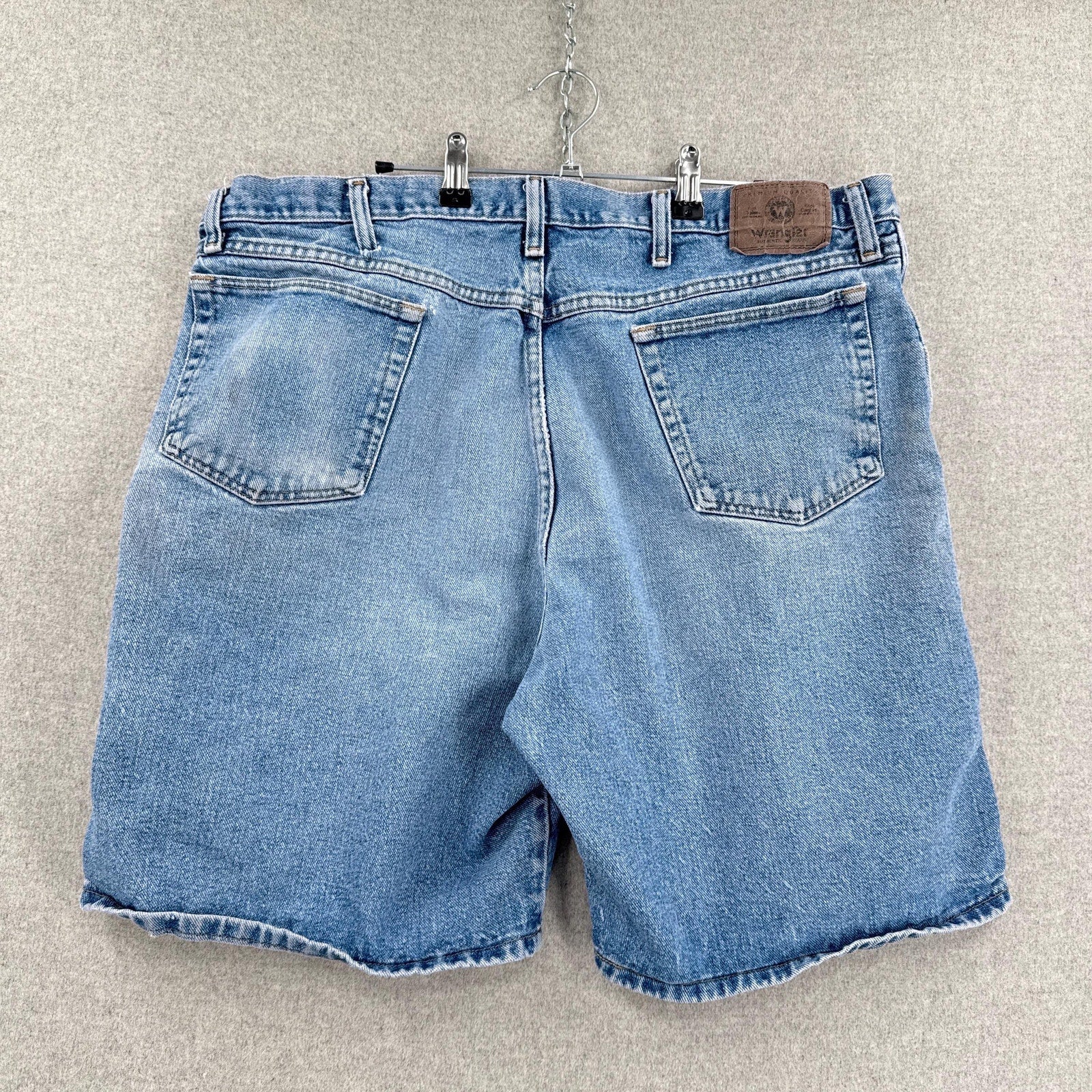 Blue denim shorts on a hanger against a neutral background