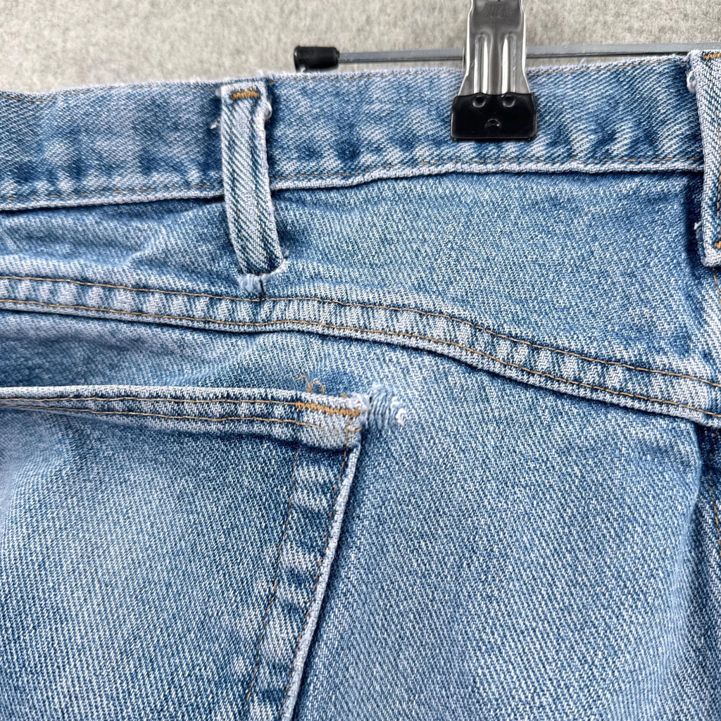 Close-up of blue jeans with a metal clip on a textured surface. rip near pocket