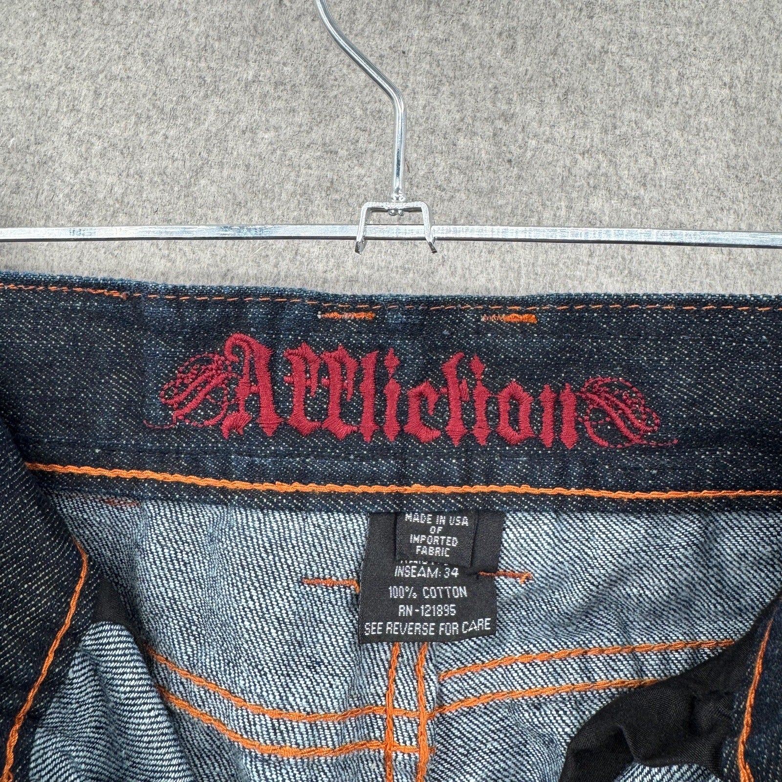 Close-up of a denim garment with Affliction branding on a hanger. Made in USA 100% cotton
