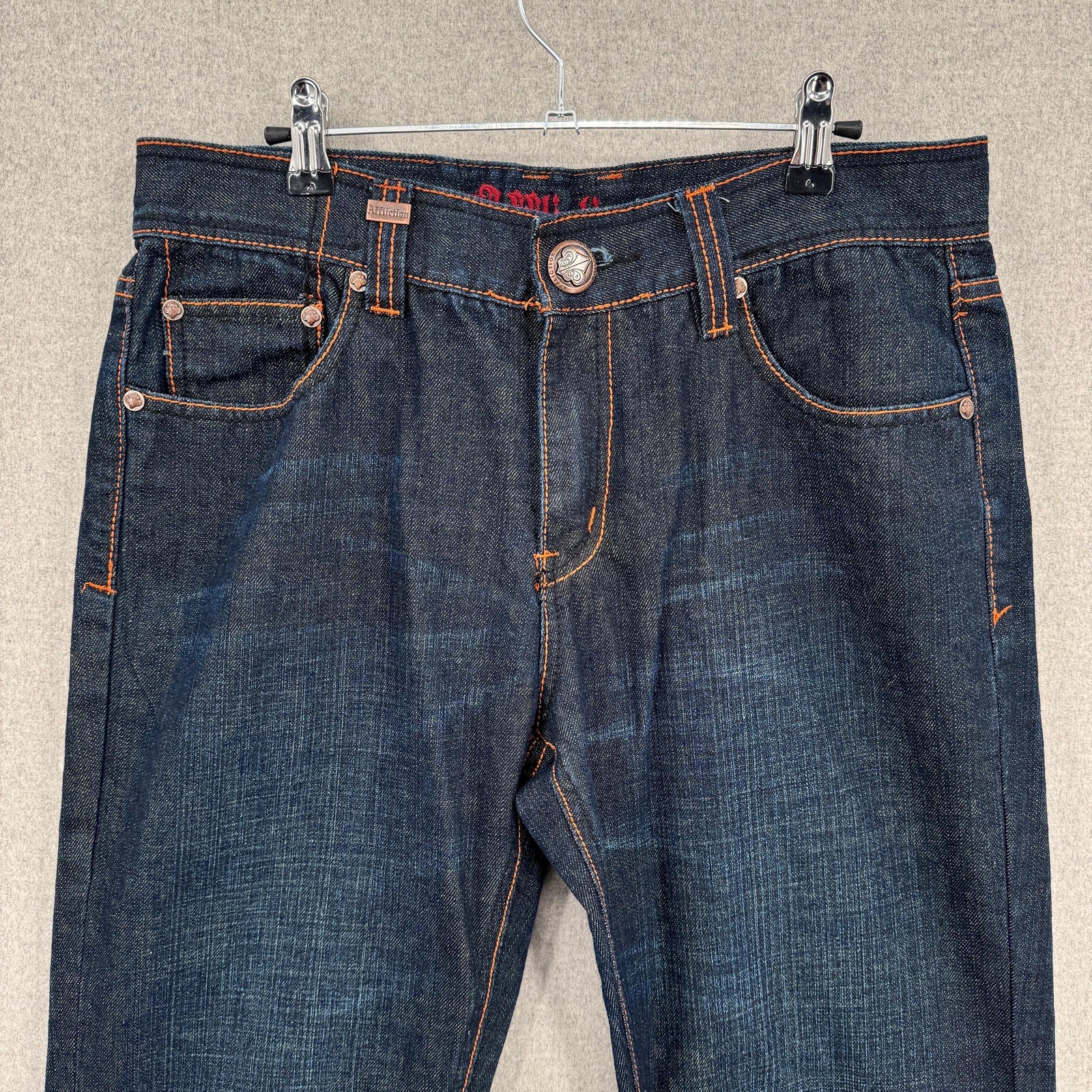 Pair of blue jeans on a hanger against a neutral background