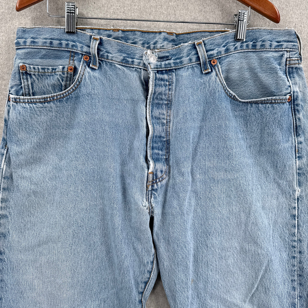 Blue jeans on a hanger against a gray background