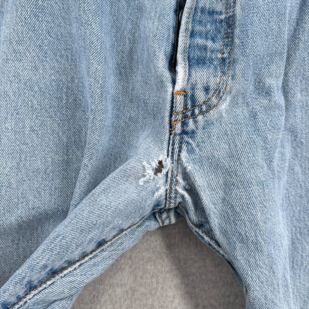 Close-up of a blue denim fabric with holes in the crotch area