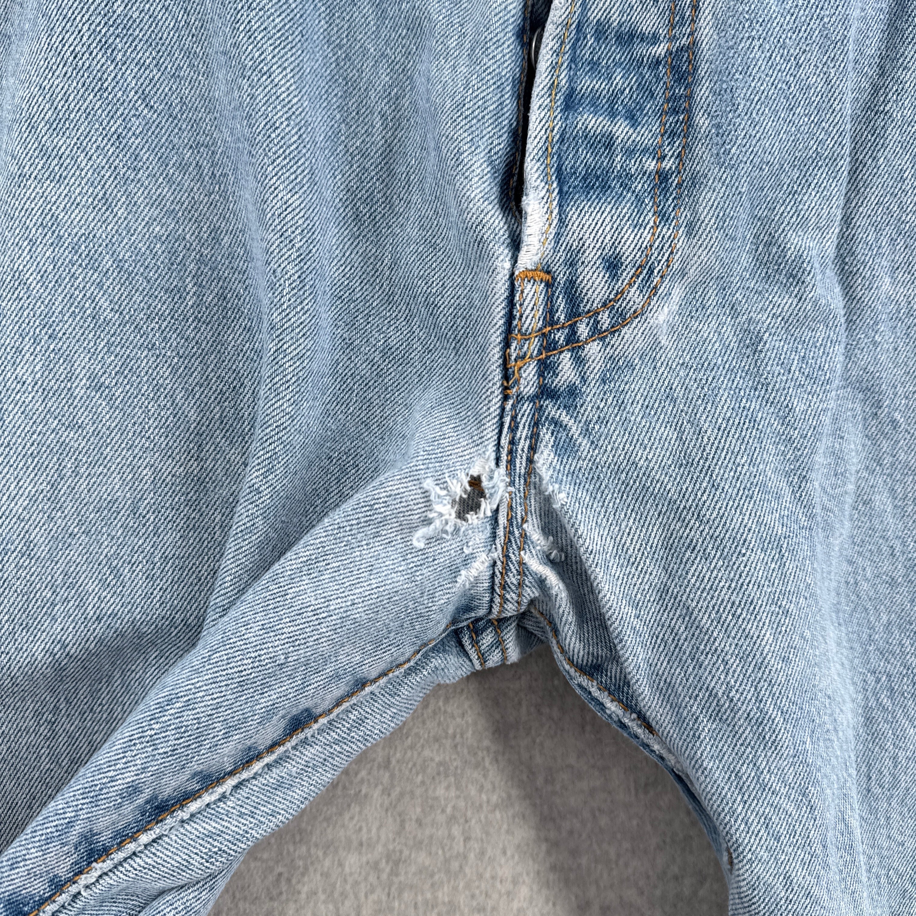 Close-up of a blue denim fabric with holes in the crotch area