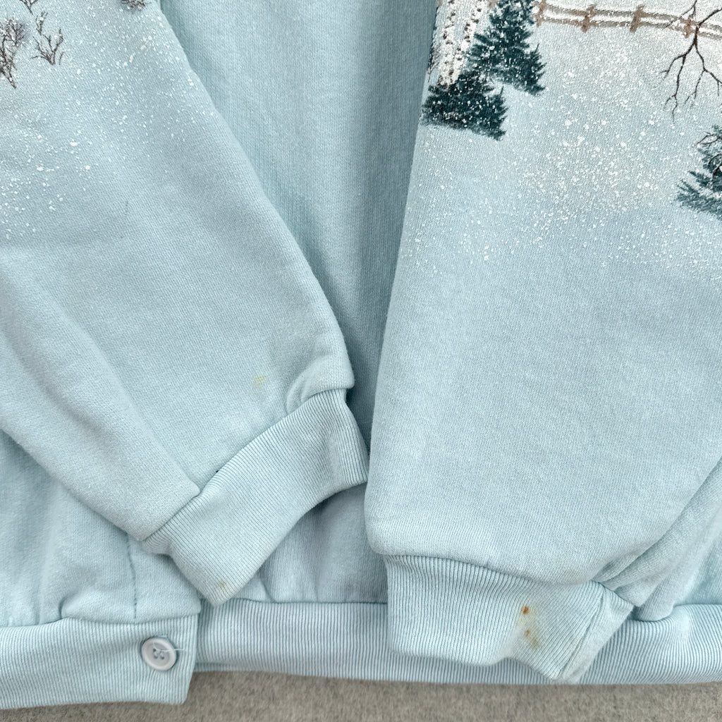 Light blue sweater with snowflakes and trees in the background showing stain spots on bottom of sleeves