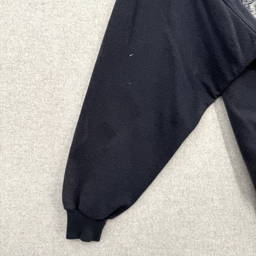 Black sweatshirt sleeve on a light gray surface. Shows some small white stain spots