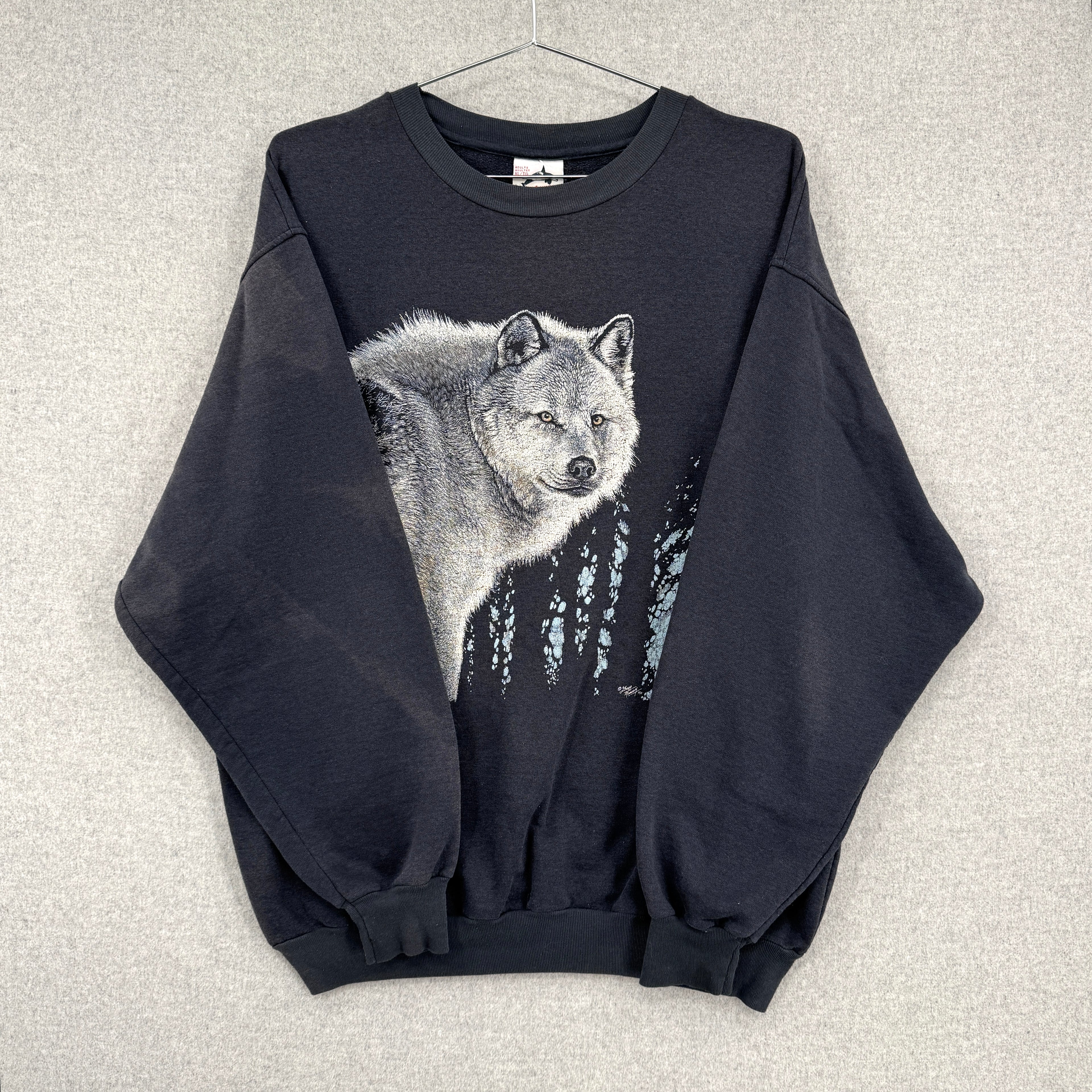 Black sweatshirt with a wolf graphic on a textured gray background. Sleeves folded over showing discolouration