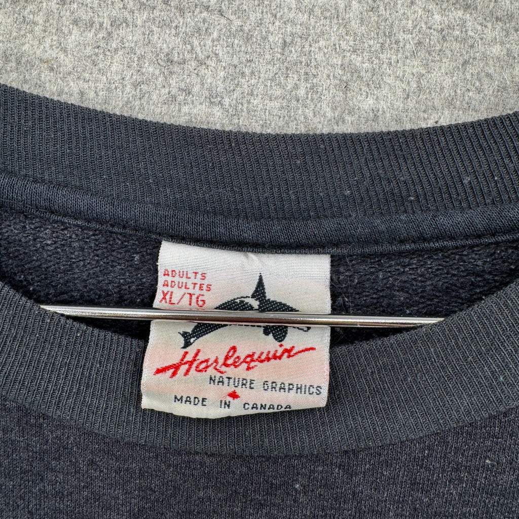 Close-up of a Harlequin label on a dark fabric background. Made in Canada, adult XL size