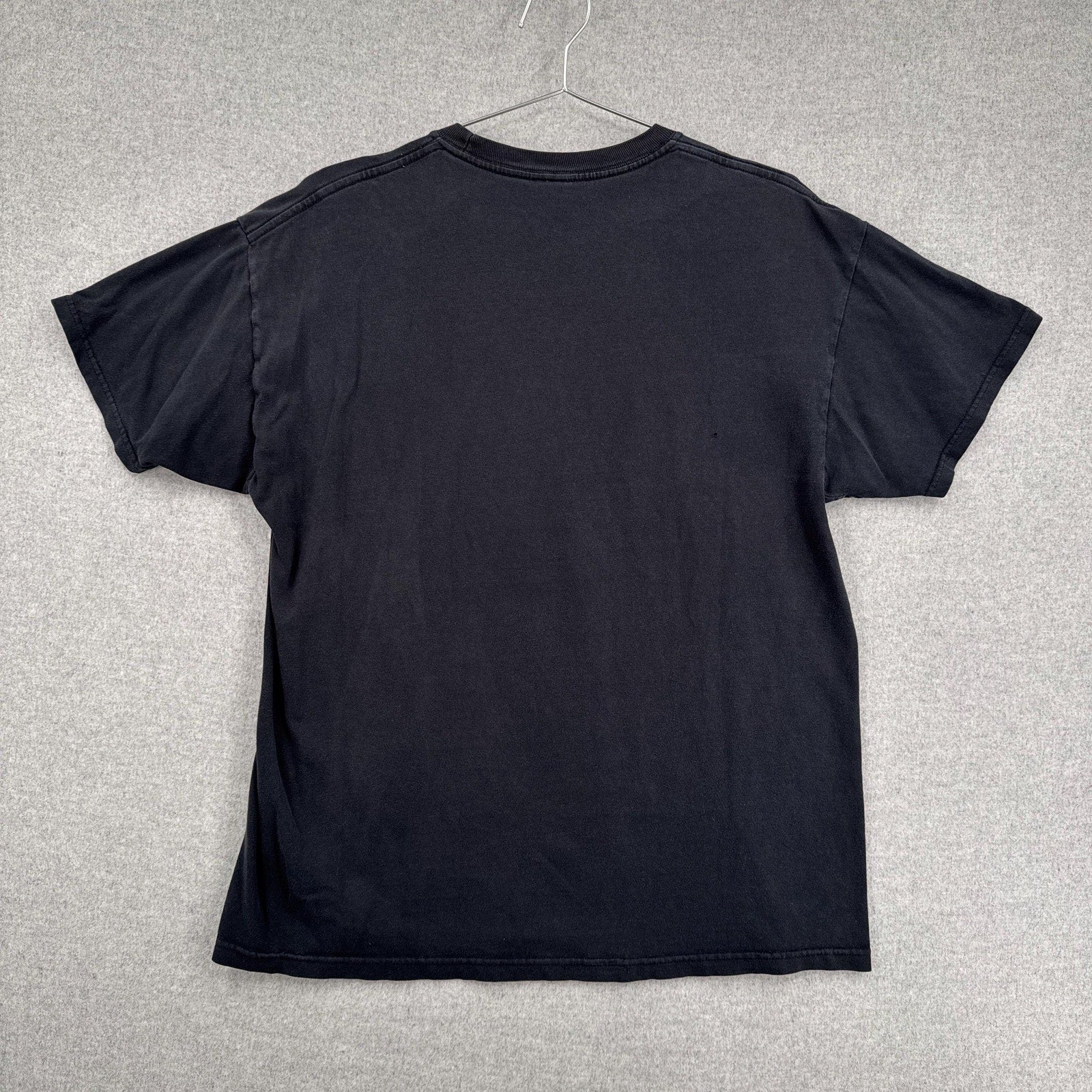 Black t-shirt on a hanger against a gray background