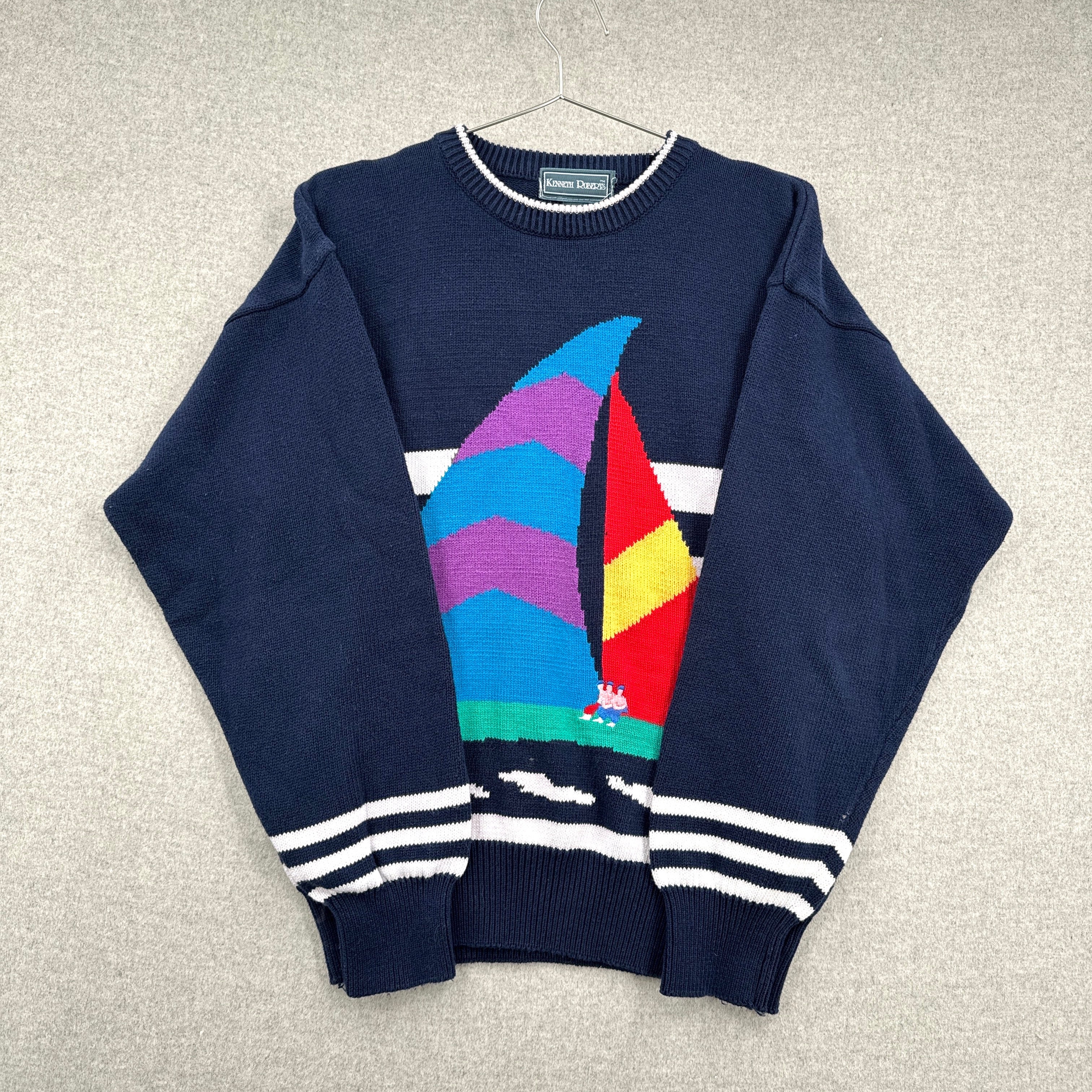 Navy blue sweater with colorful sailboat design on a light gray background